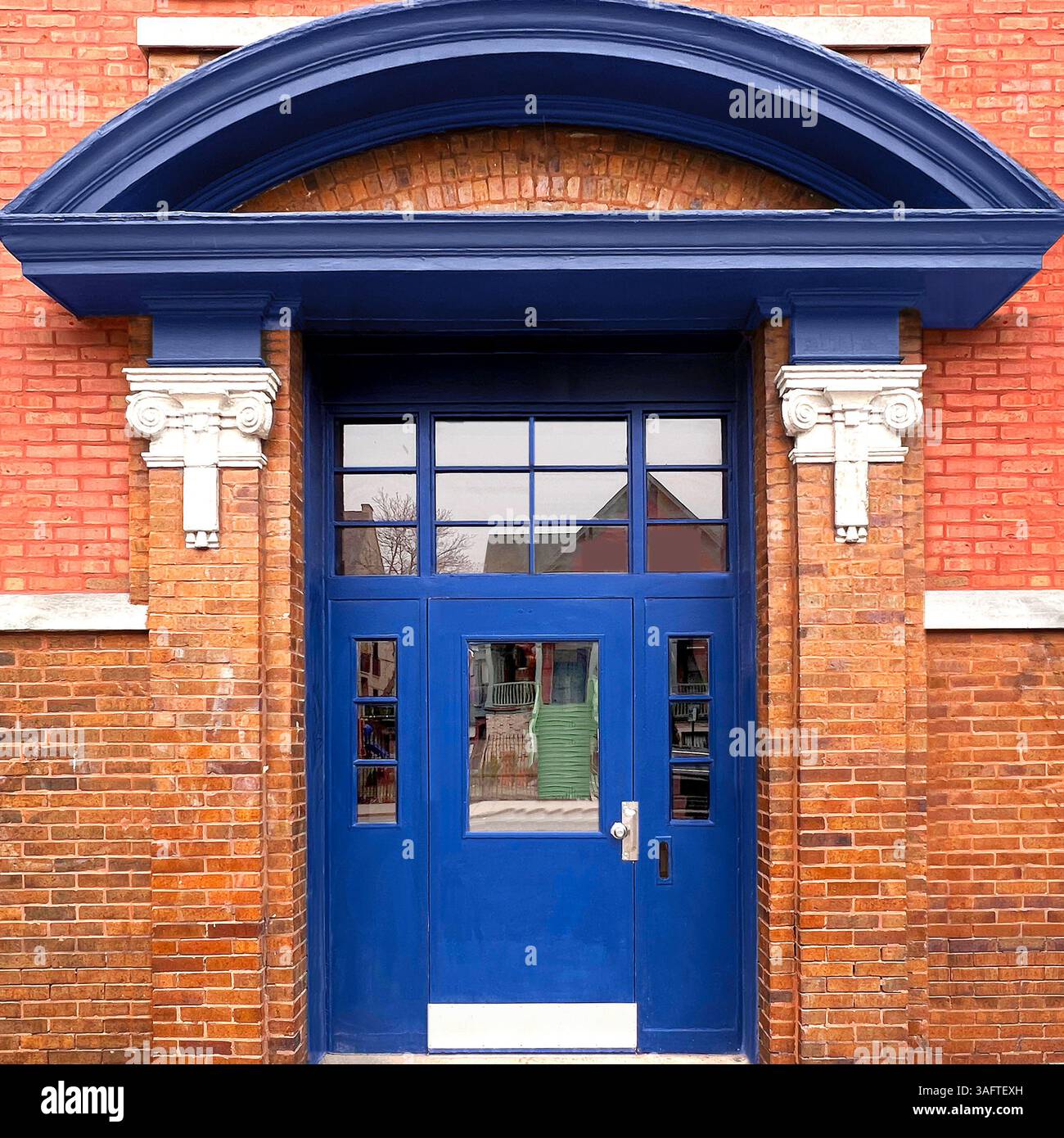Audace ingresso blu adagiato su una facciata in mattoni rossi con dettagli di colonne bianche e una sporgenza ad arco a Chicago Foto Stock
