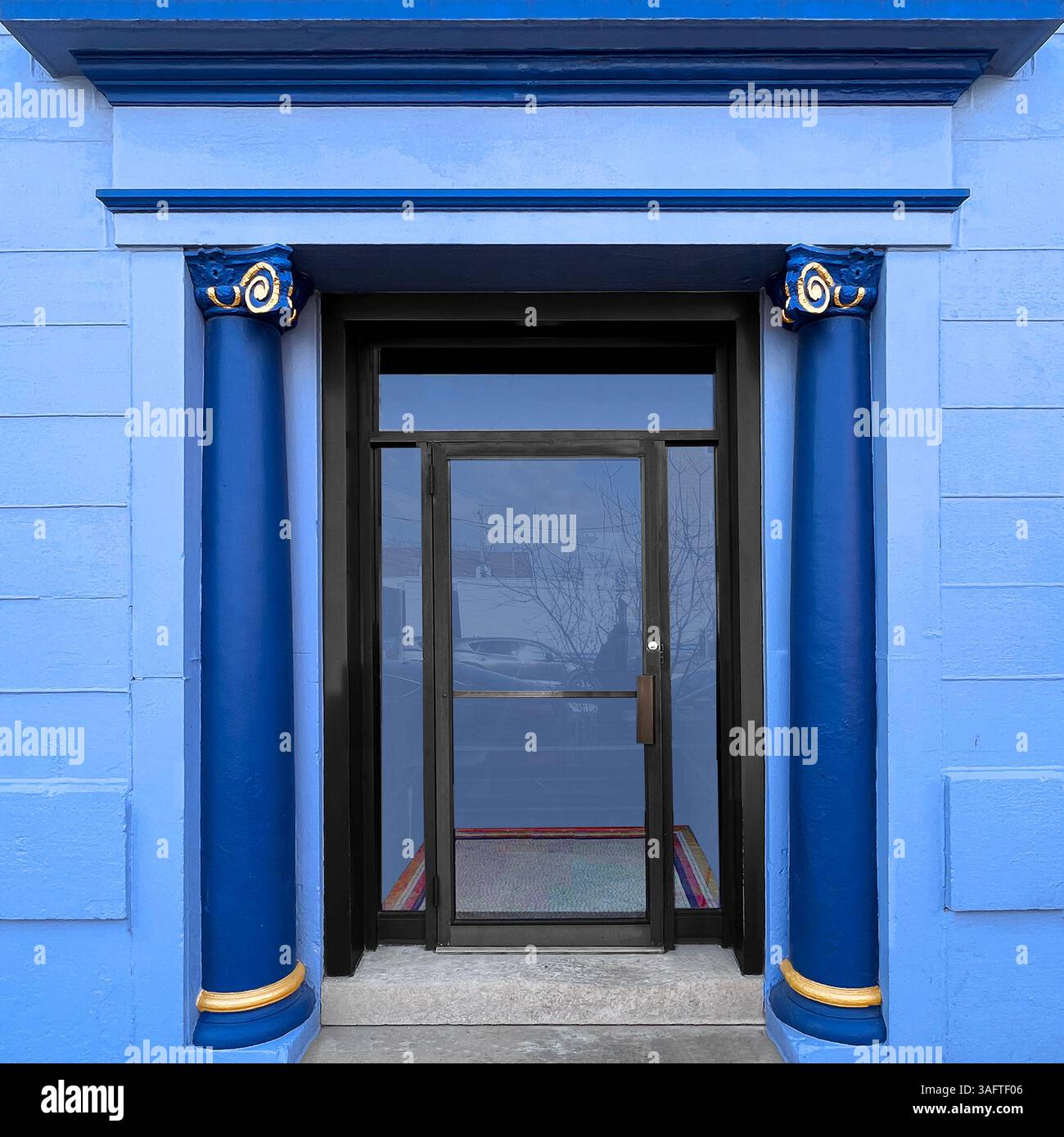 Un'entrata blu vibrante con colonne classiche e capitelli accentuati d'oro incornicia una porta di vetro a Chicago Foto Stock