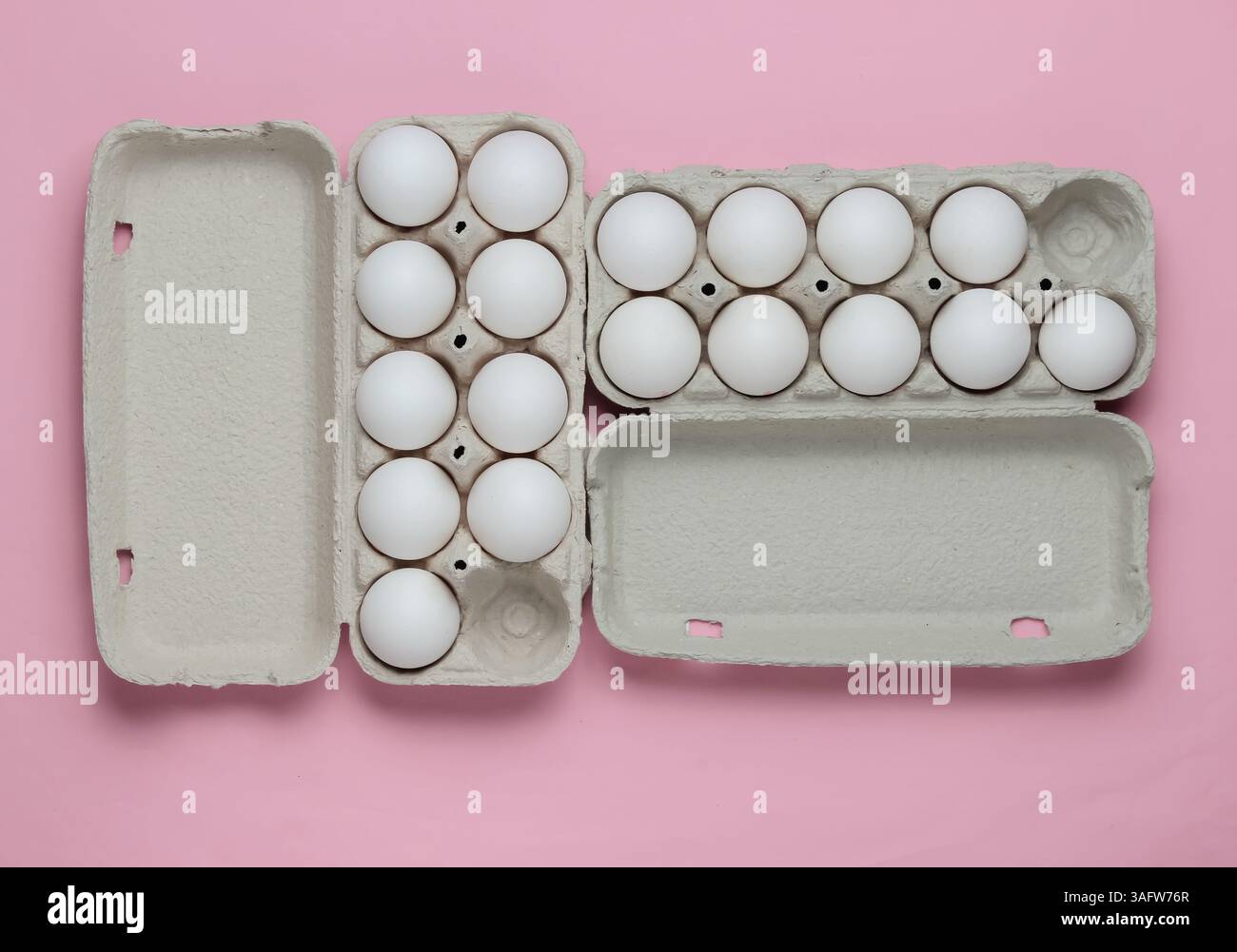 Vassoi di cartone con uova su sfondo rosa pastello. Concetto di cucina minimalista. Vista dall'alto. Foto Stock