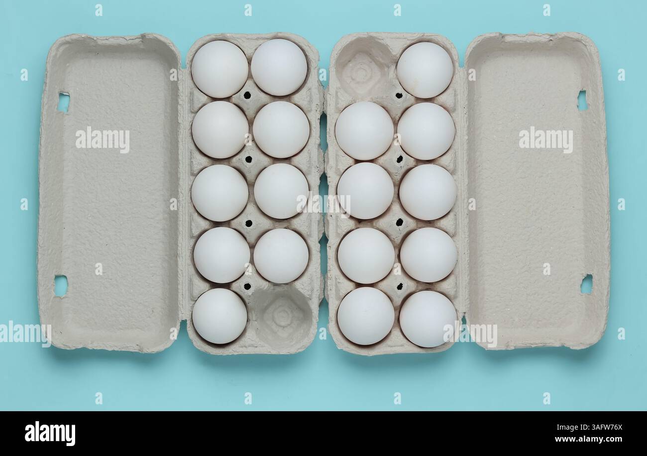 Vassoi di cartone con uova su sfondo blu pastello. Concetto di cucina minimalista. Vista dall'alto. Foto Stock