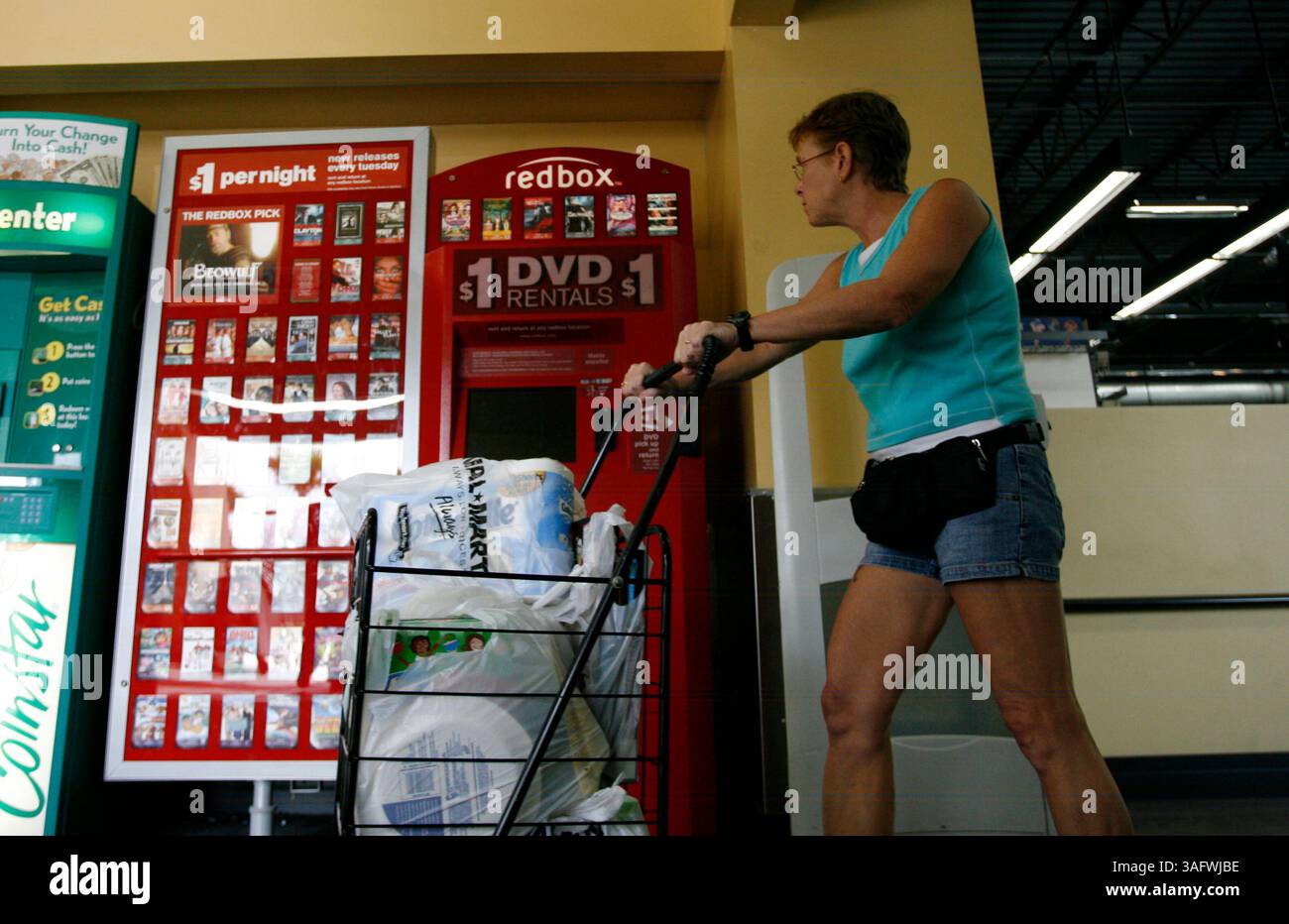 Tampa 2/26/08)--1) Shoppers at the Wal-Mart Neigbhrhood Market, passa una nuova macchina Red Box martedì mattina. Red Box è un chiosco di distributori automatici che si trova accanto alla porta di molti rivenditori che distribuiscono circa 100 DVD diversi per un giorno. Ci sono già più macchine distribuite là fuori, in quanto ci sono negozi di video di successo e molti altri sono stati testati da Publix, Walgreens, Albertsons e Winn-Dixie. (Immagine di credito: St Petersburg Times/ZUMAPRESS.com) Foto Stock