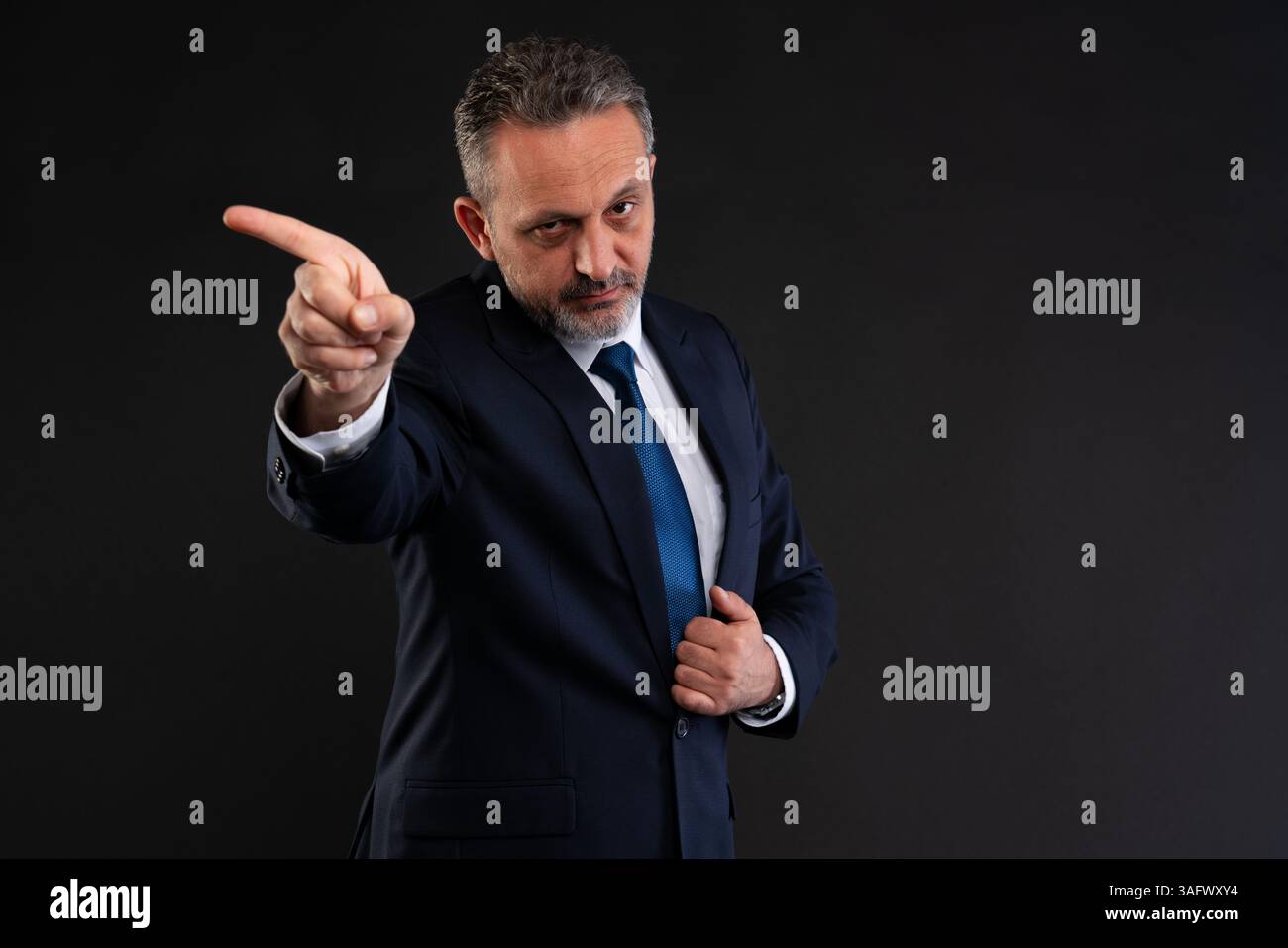 Un uomo d'affari serio che punta assertivamente al fianco, esprime autorità o dà direzione in un ambiente aziendale. Foto Stock