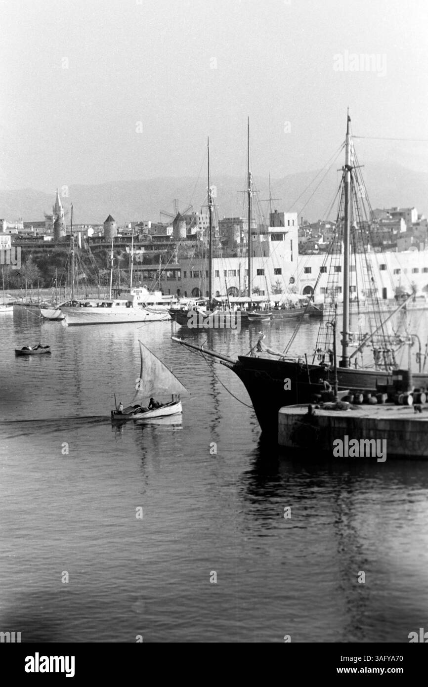 Im Hafen von Mallorca finden sich neben Zweimastern und Yachten ebenso kleinere Wasserfahrzeuge, wie Fischerboote mit oder ohne Segel, die in der Morgensonne die Bucht durchqueren, Mallorca 1957. Il porto di Maiorca ospita due maestri e yacht, nonché imbarcazioni più piccole, come barche da pesca con o senza vele, che si spostano attraverso la baia al sole del mattino, Mallorca 1957. Foto Stock
