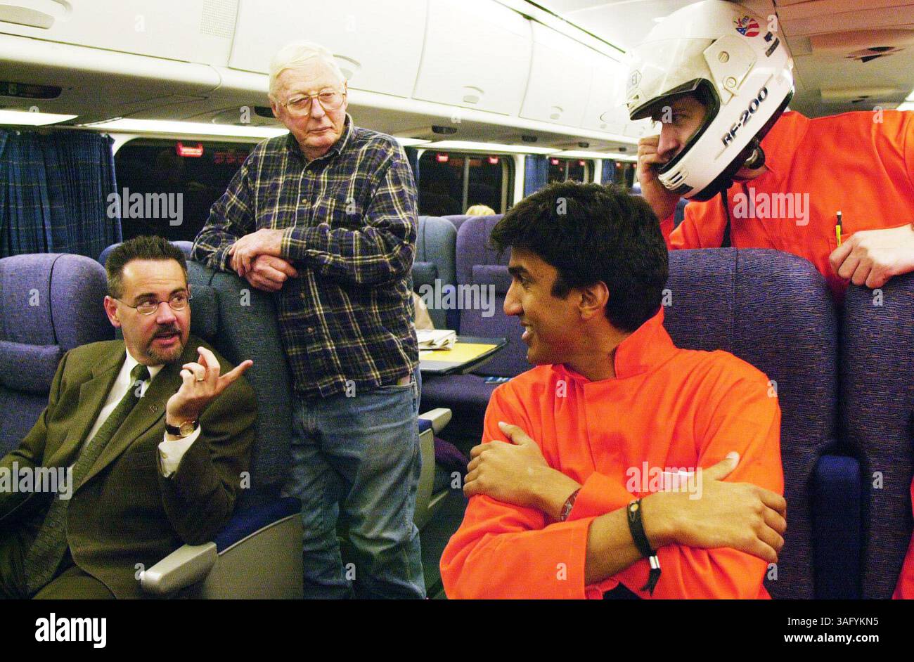 il presidente e amministratore delegato della Amtrak, George D. Warrington, a sinistra, e il passeggero Alexander Clelland guardano in modo curioso Ravi Jain, secondo da destra, e John Carrera, a destra, lunedì mattina, la corsa inaugurale del servizio Acela per il pubblico. Il signor Jain e il signor Carrera insieme ad altri due vestiti allo stesso modo hanno viaggiato sul treno Acela da Washington a Boston lunedì. Vengono da Boston e si chiamano 3 Speed 2000. I quattro stavano filmando il loro viaggio dove si definivano pionieri del trasporto con sede a Boston e volevano incontrare il signor Warrington per congratularsi con lui "come capitano della nave". Foto Stock