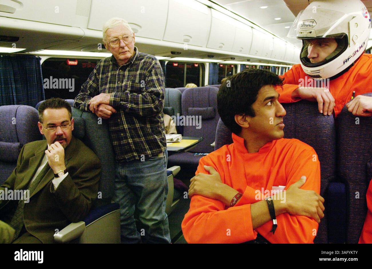 il presidente e amministratore delegato della Amtrak, George D. Warrington, a sinistra, e il passeggero Alexander Clelland guardano in modo curioso Ravi Jain, secondo da destra, e John Carrera, a destra, lunedì mattina, la corsa inaugurale del servizio Acela per il pubblico. Il signor Jain e il signor Carrera, insieme ad altri due vestiti in modo simile con tute e caschi arancioni, hanno viaggiato sul treno Acela da Washington a Boston lunedì. Vengono da Boston e si chiamano 3 Speed 2000. I quattro stavano filmando il loro viaggio dove si definivano pionieri del trasporto con sede a Boston e volevano incontrare Mr. Warrington per congratularsi con lui Foto Stock