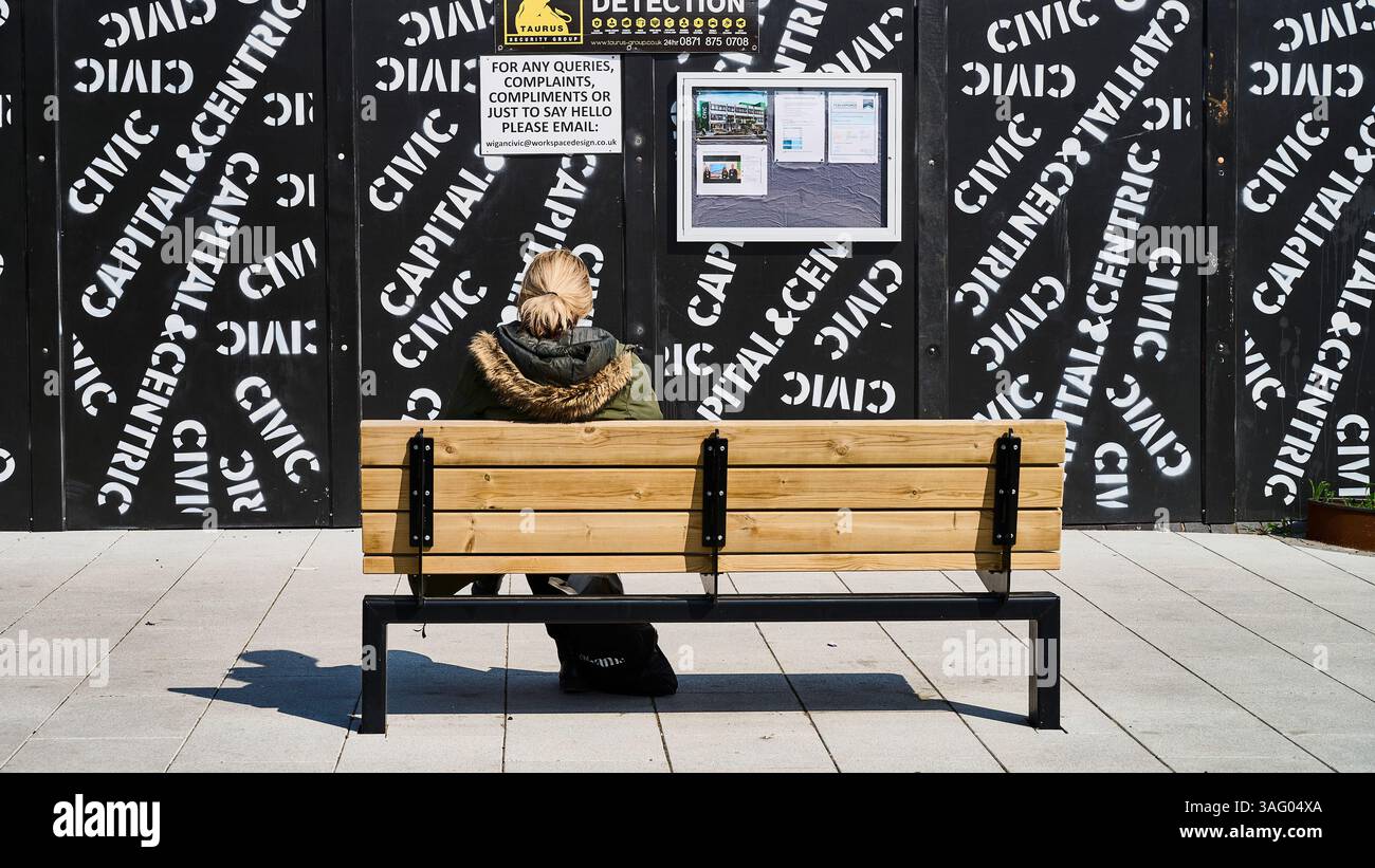 Giovani donne con schiena alla macchina fotografica sedute di fronte all'edificio che si accumula Foto Stock