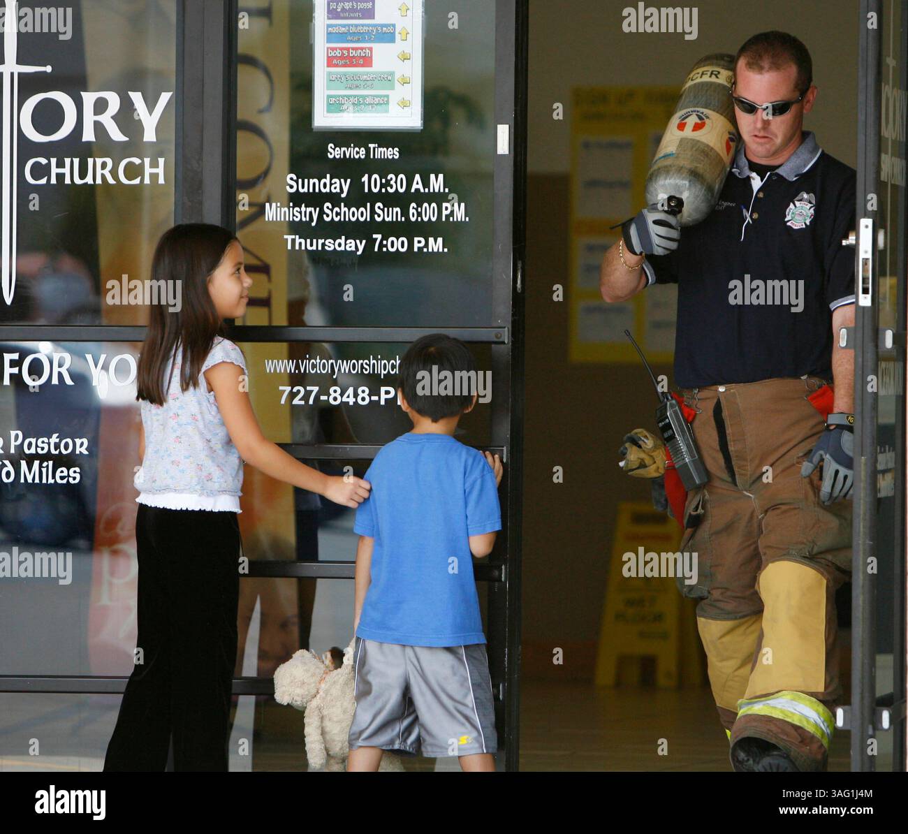 DIDASCALIA : FOTO 1 : [festività - GIOVEDÌ - 07/19/2007] i bambini si allontanano dal cammino mentre un vigile del fuoco esce dall'edificio presso la Victory Worship Church presso Universal Plaza in Holiday giovedì 19/7/07, dove le unità hanno risposto a una chiamata di fumo nell'edificio. Dopo aver controllato l'edificio e aver usato una termocamera, hanno osservato una foschia nell'edificio, ma non c'erano fumo o fuoco..LANCE ARAM ROTHSTEIN | Times..Descrizione : PT 271040 ROTH Nofire. . I vigili del fuoco della contea di Pasco rispondono a una chiamata di fumo nell'edificio della chiesa di culto della Vittoria in vacanza giovedì 19/7. (Immagine di credito: St Petersburg Times/ZUMAPR Foto Stock