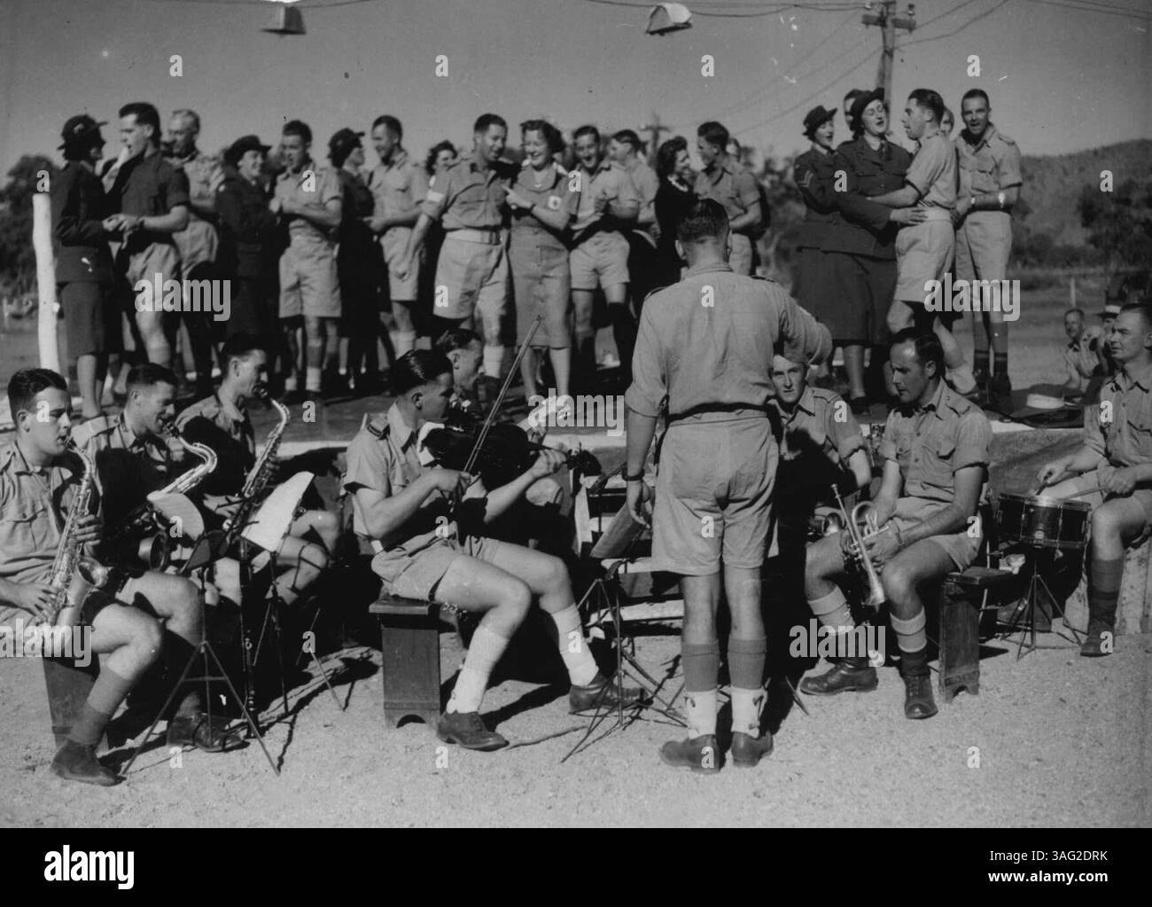 Commedia musicale continua -- scatti dell'esercito scattati nel quartiere di Alice Springs . . . Scena generale con VIP e infermieri e personale dell'esercito con orchestra in primo piano. Al centro del palco V.A.D.L. Barnes e Sgt. E.R.G. Hawkins cantano una commedia Love Song. Per l'identificazione - sono quasi tra le braccia degli altri. 26 luglio 1943. (Foto di H. Rodda). Foto Stock