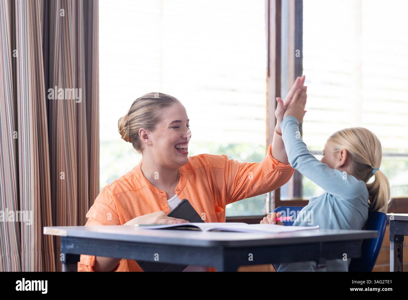 A scuola, professoressa e studentessa di alto livello mentre lavorava alla scrivania Foto Stock