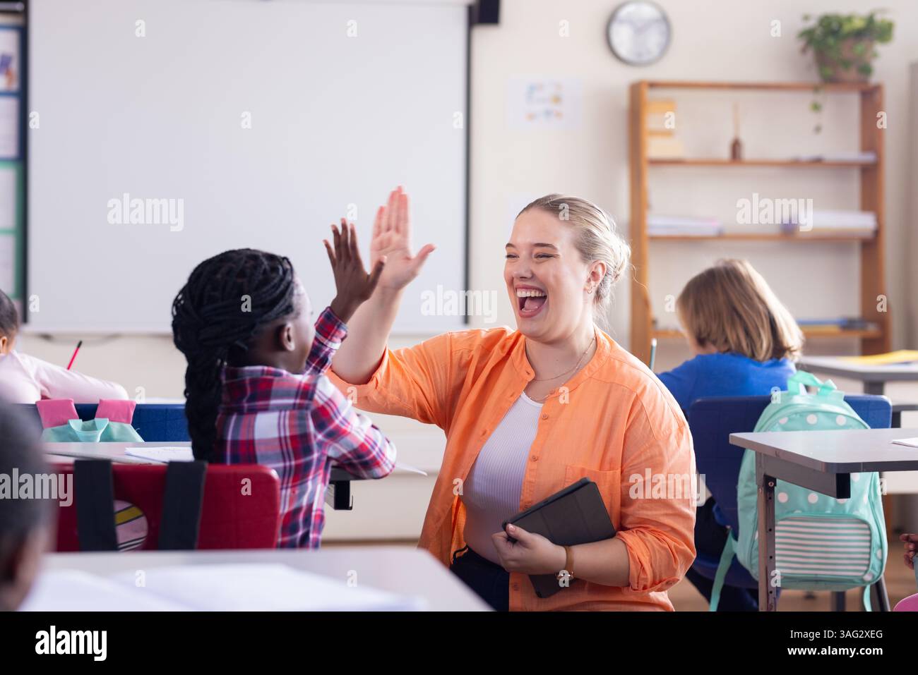Ragazza afroamericana di alto livello in classe, insegnante donna che celebra i risultati a scuola Foto Stock
