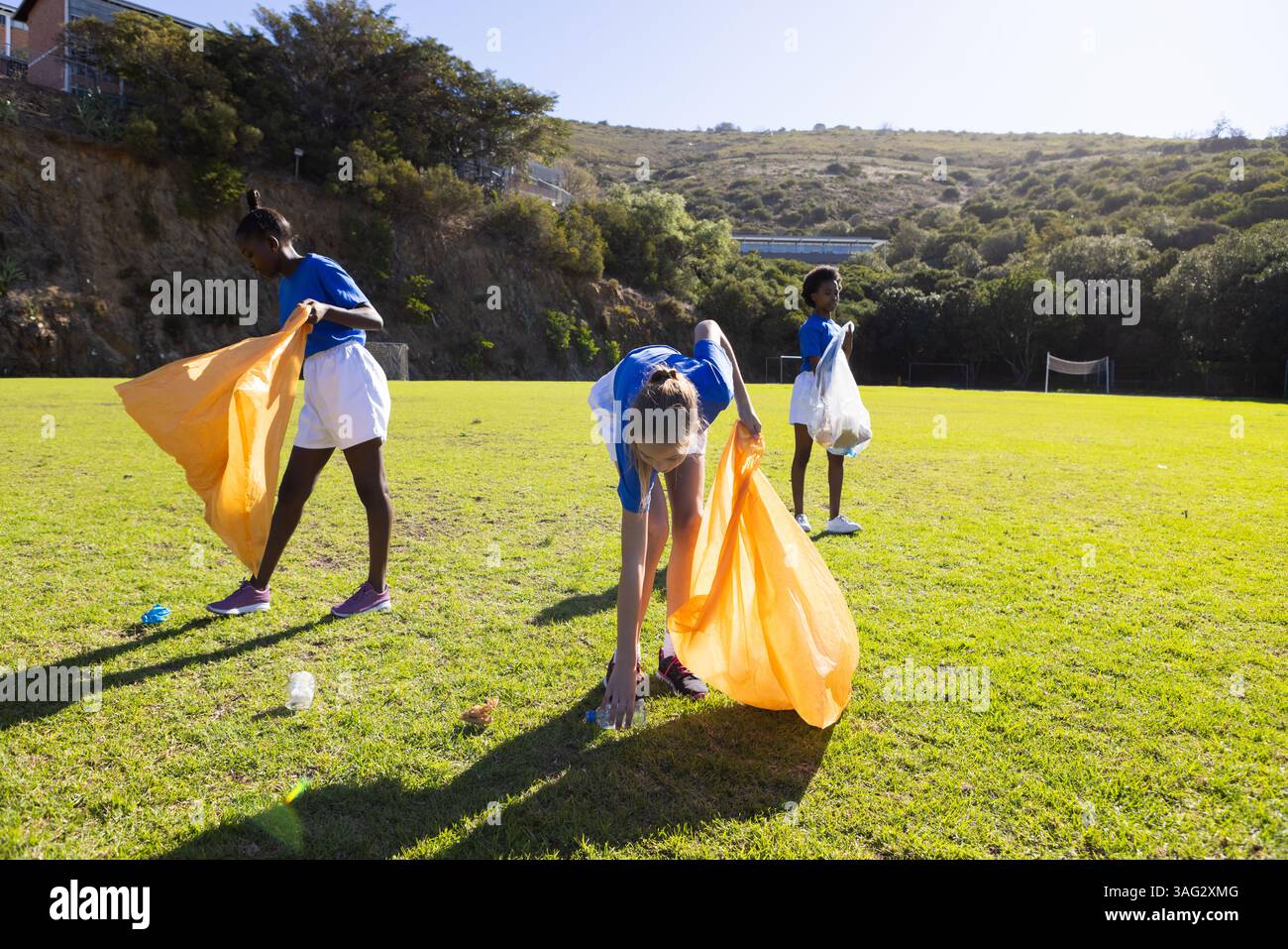 A scuola, ragazze diverse raccolgono spazzatura sul campo, partecipano ad attività di pulizia Foto Stock