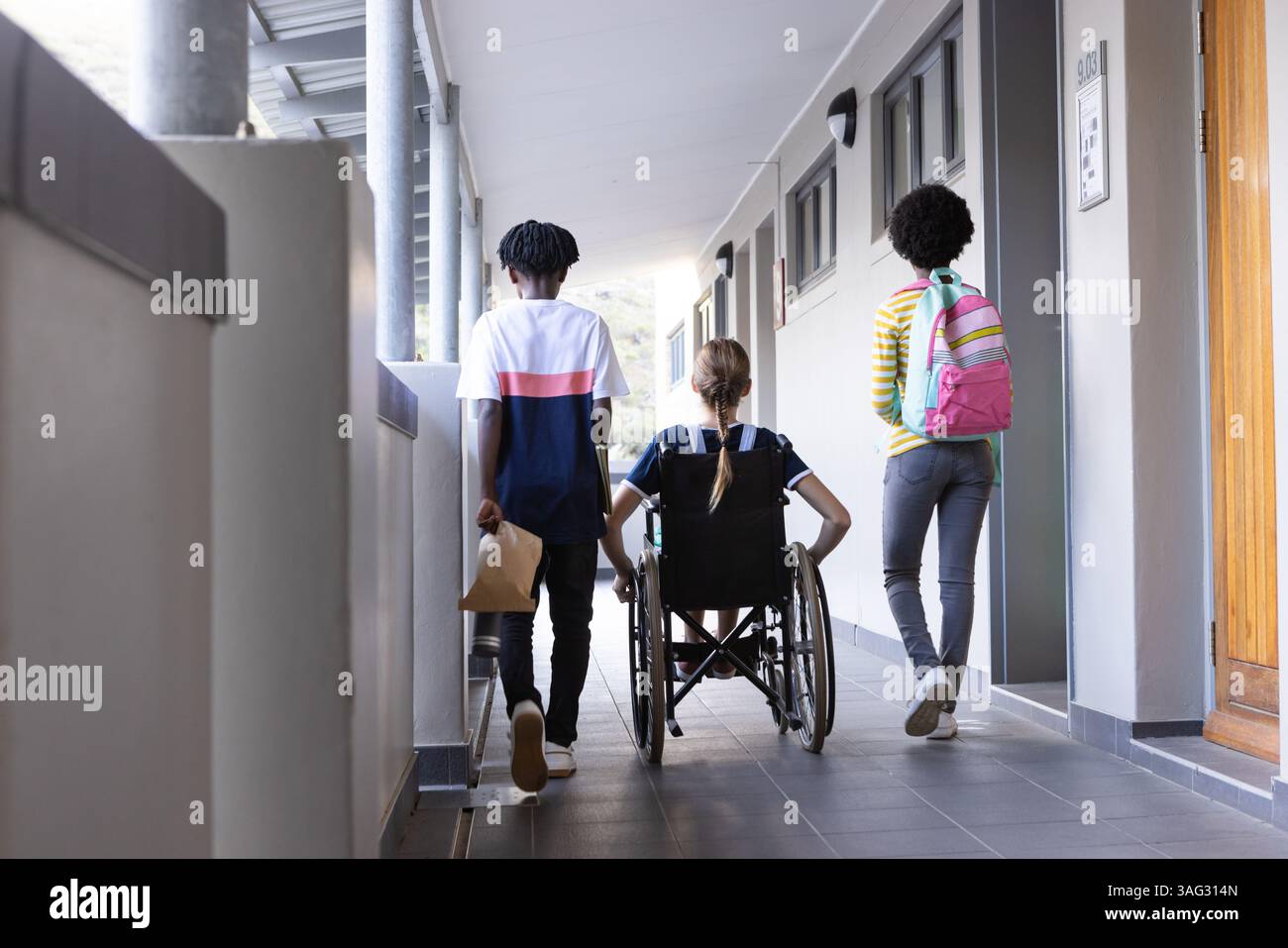 Camminando nei corridoi scolastici, diversi studenti con zaini e sedie a rotelle, si dirigono a lezione Foto Stock