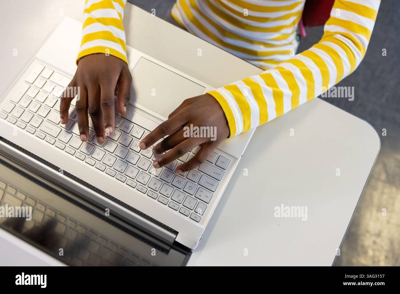 Digitando sul laptop, ragazza afroamericana a scuola concentrata sul lavoro alla scrivania Foto Stock