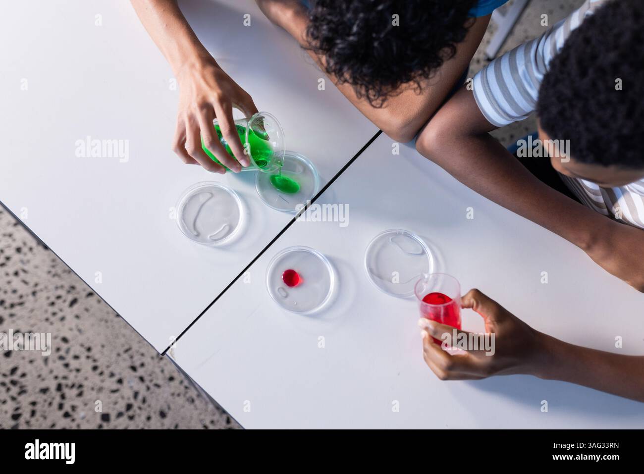 Condurre esperimenti scientifici con liquidi colorati e piatti di Petri, studenti a scuola Foto Stock