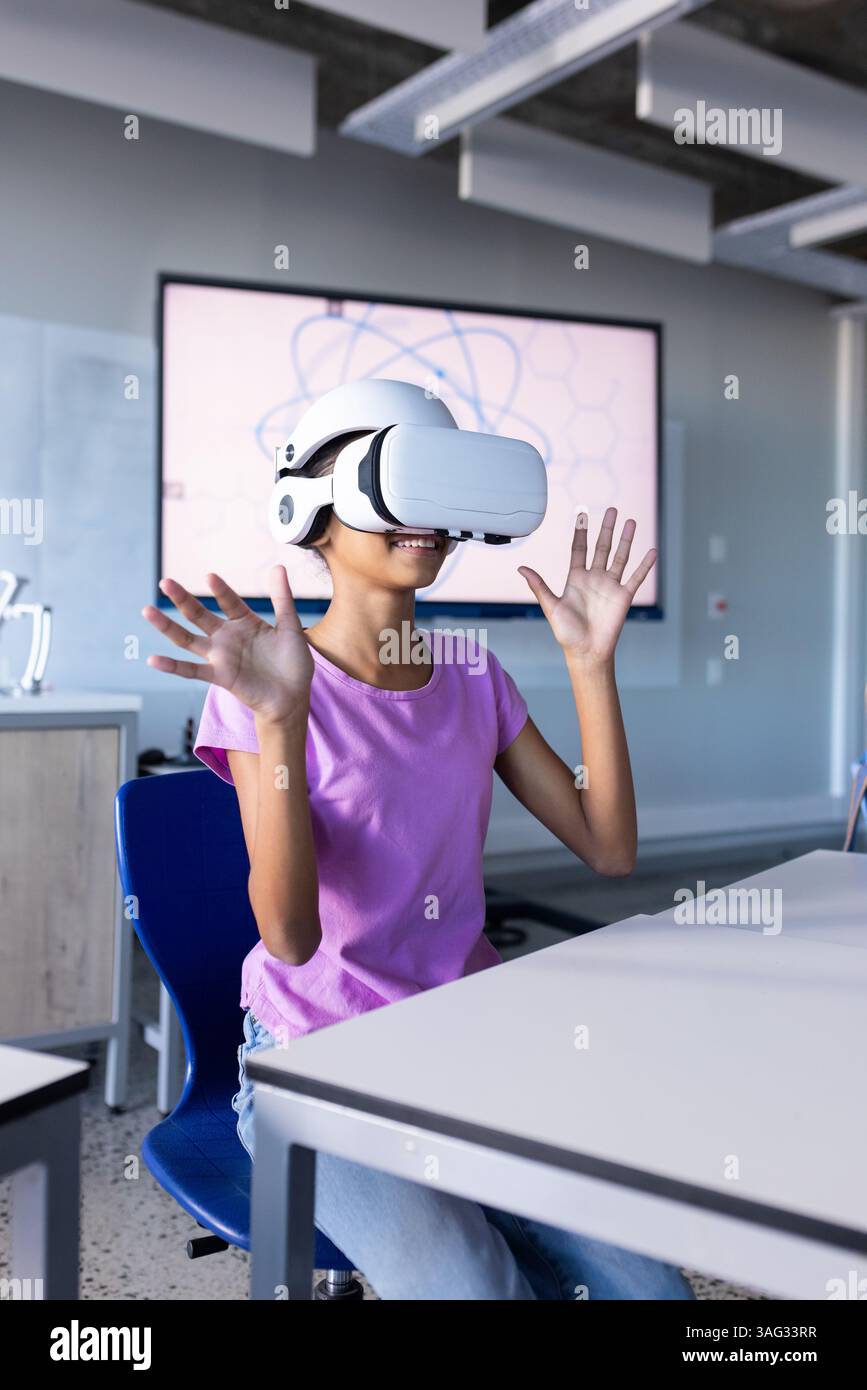 Utilizzando il visore VR, studente in classe scolastica che sperimenta la realtà virtuale Foto Stock