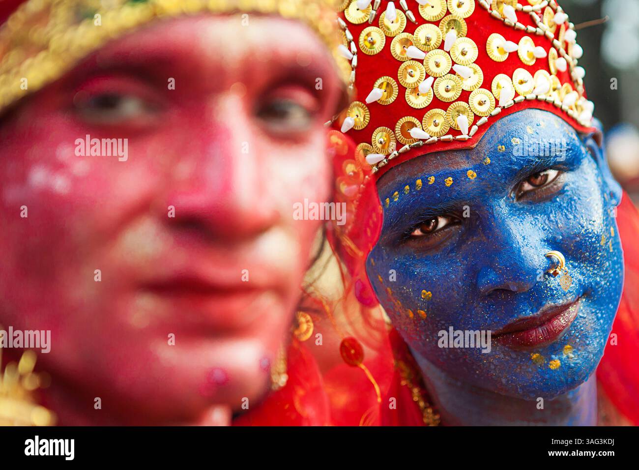 Primo piano di uomini indiani con volti dipinti come divinità indù durante un festival culturale di strada in India, che mostra costumi ed espressioni tradizionali. Foto Stock
