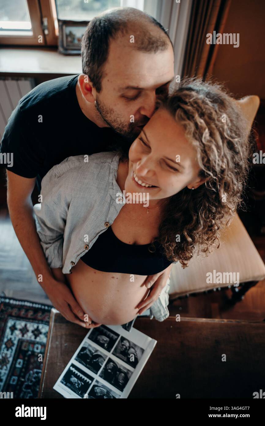 Le coppie in attesa condividono un momento di gioia mentre abbracciano e visualizzano le immagini a ultrasuoni, evidenziando la loro emozione e attesa. Il supp del partner Foto Stock