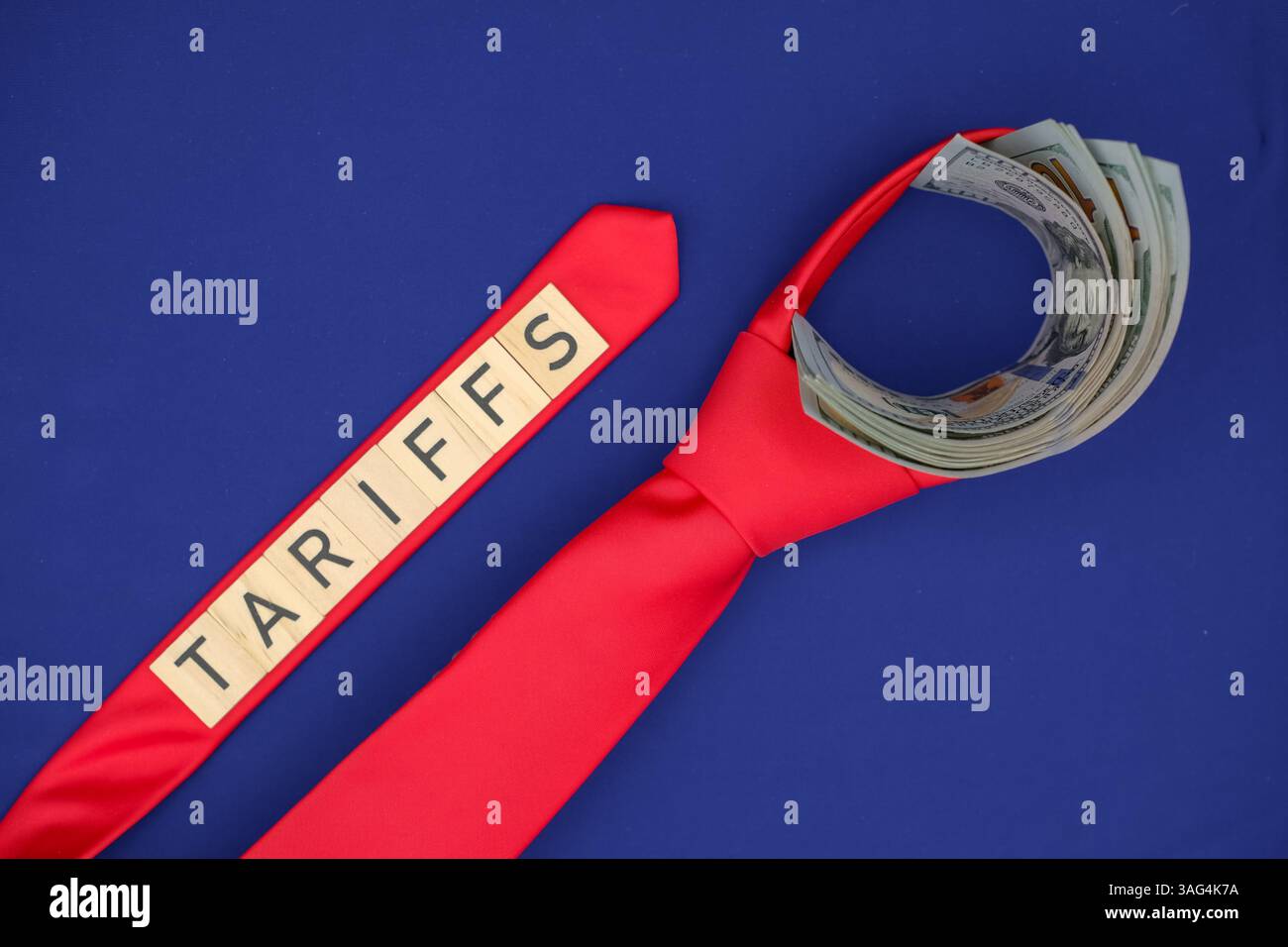 Immagine concettuale che rappresenta la pressione finanziaria e i vincoli economici. Banconote in dollari circondate da una cravatta rossa su sfondo blu, parola "tariffe". Foto Stock