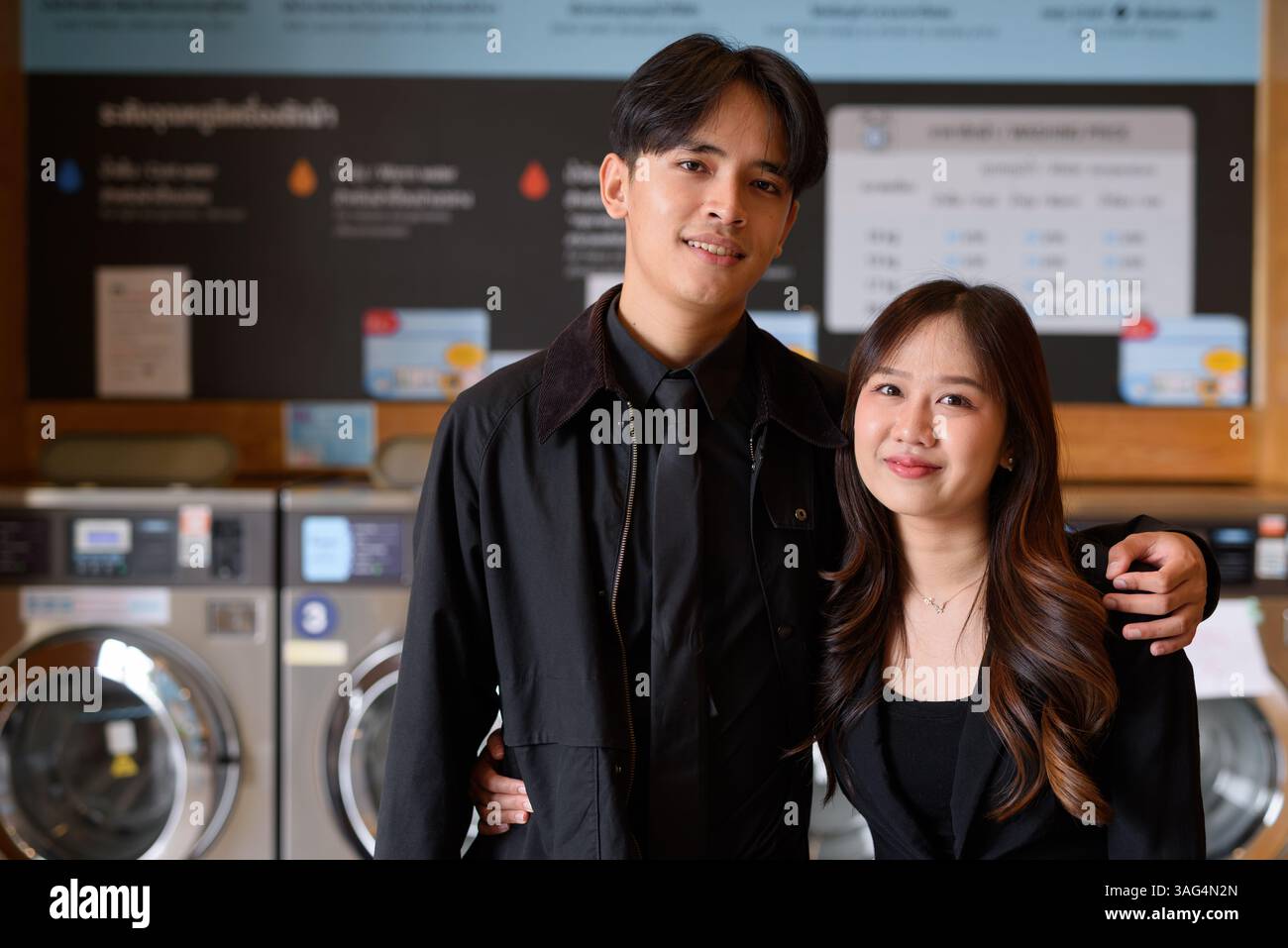 Ritratto di una coppia asiatica in un negozio di lavanderia che guarda la macchina fotografica Foto Stock