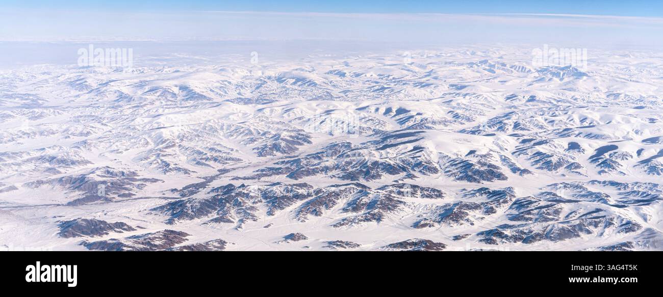 Vista mozzafiato ad alta quota delle montagne innevate di Tangula sull'altopiano tibetano in Cina, vista dalla finestra di un aeroplano durante Foto Stock