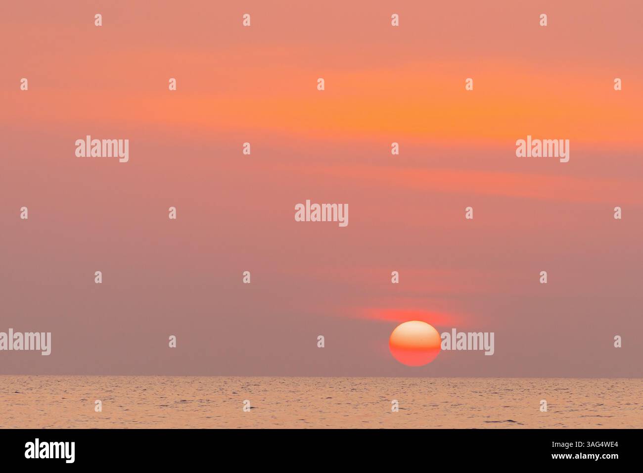 Un tramonto mozzafiato che dipinge il cielo su un oceano sereno con onde dolci e sfumature morbide e accattivanti, Un tramonto mozzafiato dipinge gradualmente il sk Foto Stock
