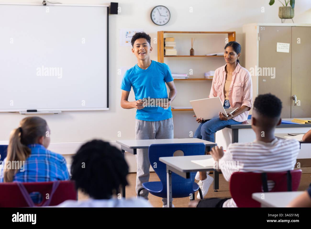 Presentazione del progetto a scuola, ragazzo che tiene un tablet mentre un'insegnante indiana e gli studenti guardano Foto Stock