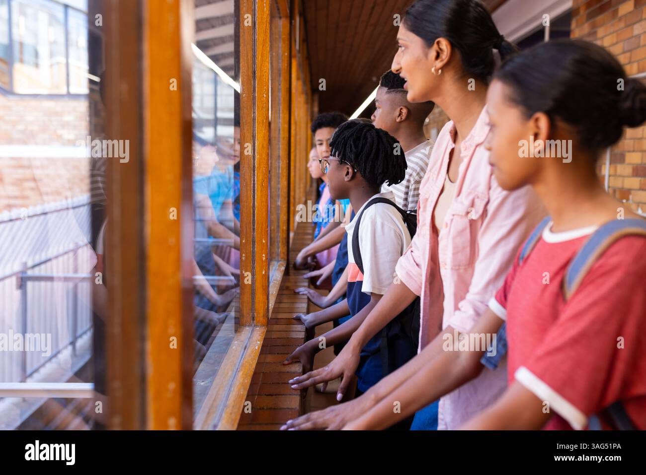 Studentesse e insegnante indiana che guardano fuori dalla finestra, osservano fuori dall'edificio scolastico, spazio copia Foto Stock