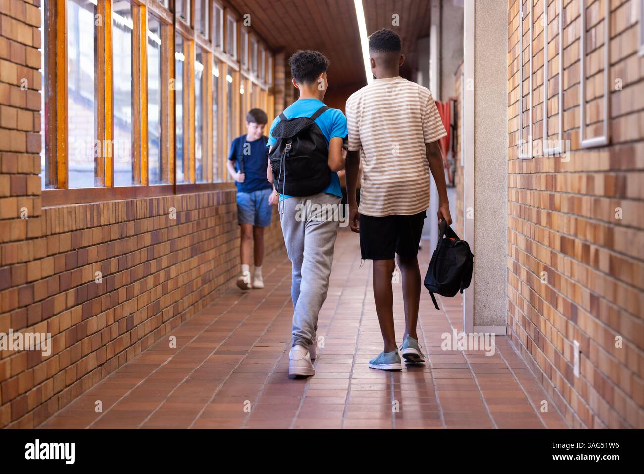 Camminando nel corridoio della scuola, due ragazzi con zaini diretti a lezione Foto Stock
