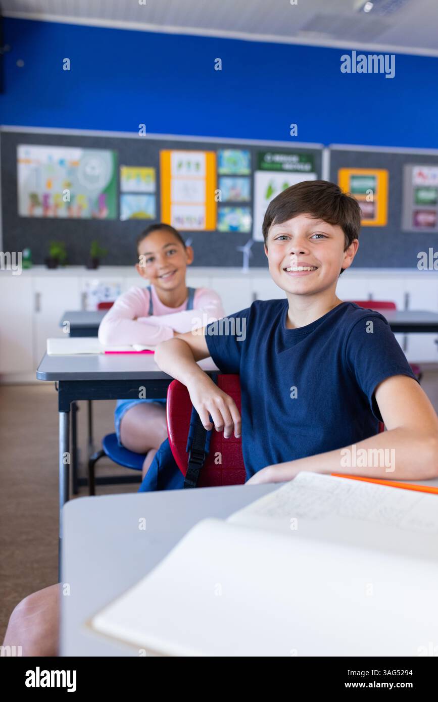 Studenti sorridenti seduti alle scrivanie in classe, impegnati in attività scolastiche Foto Stock