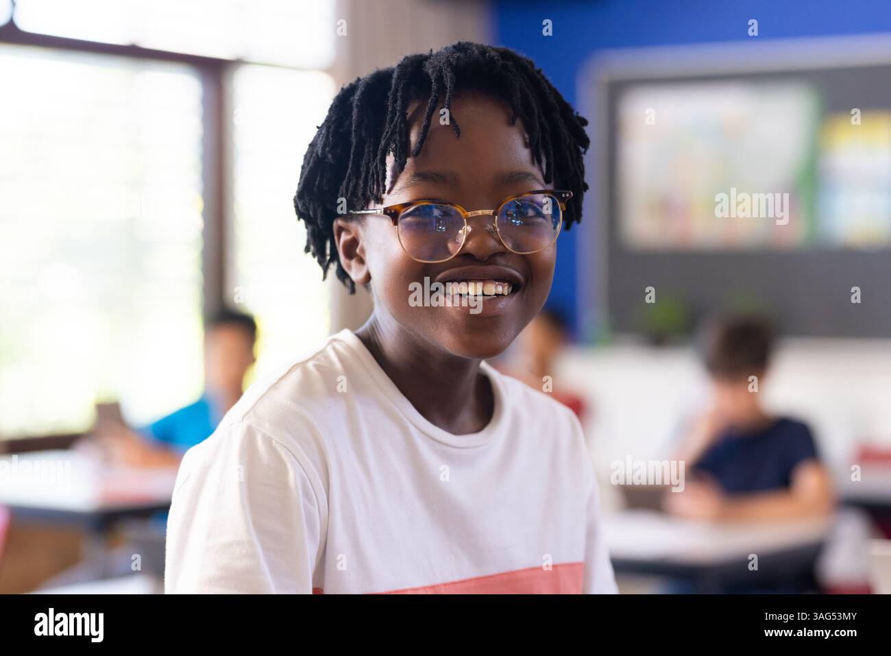 Indossa gli occhiali, sorridi ragazzo che si gode l'ambiente scolastico in classe Foto Stock