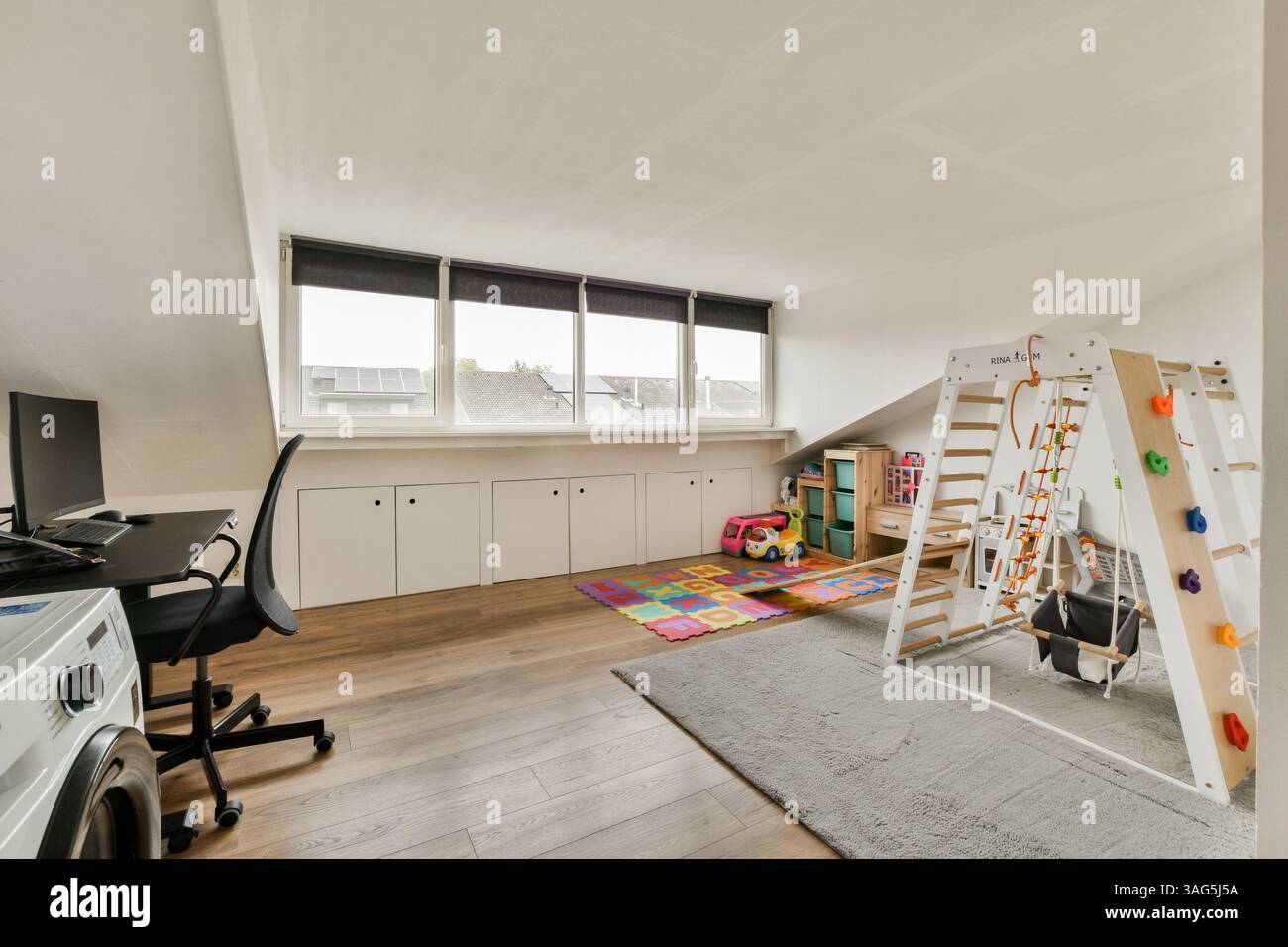 Una vivace sala giochi con una disposizione confortevole, pavimento colorato e molta luce naturale. Progettata per il comfort e le attività per i bambini, è funzionale e invitante. Foto Stock