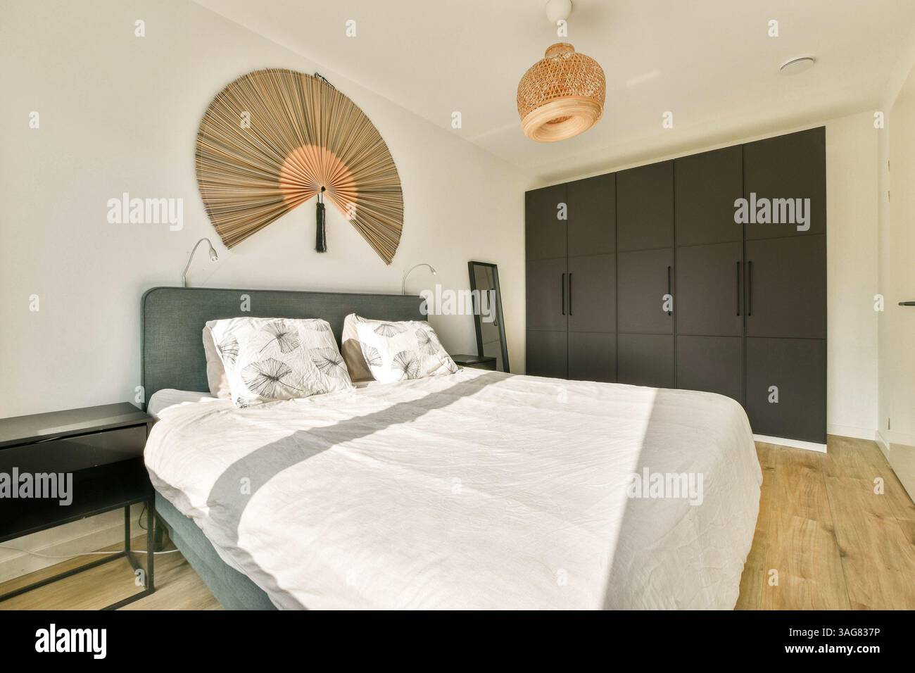 Una camera moderna ed elegante con un soffice letto, pareti decorative e arredi minimalisti che creano un'atmosfera accogliente. Foto Stock