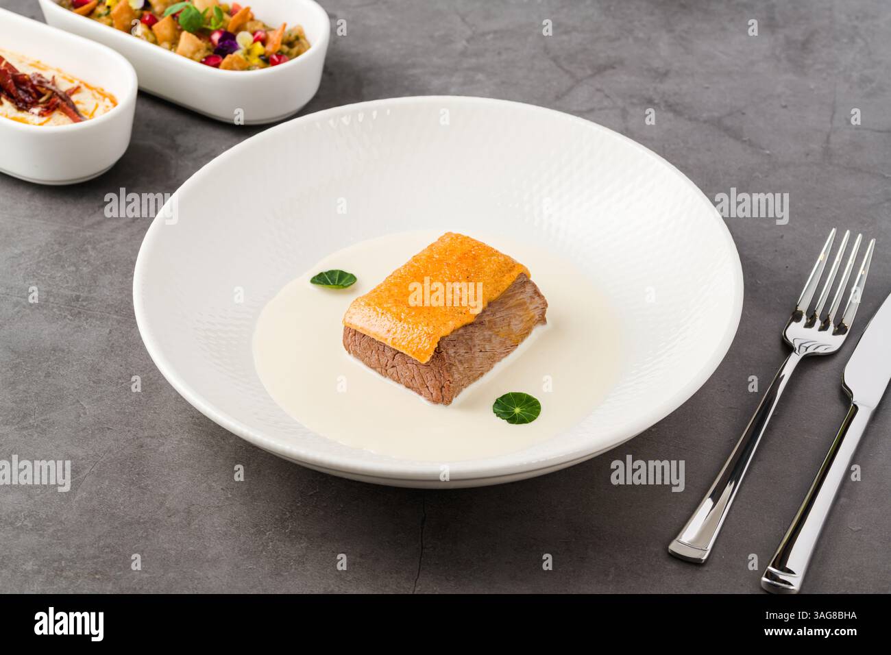 Manzo gourmet servito con salsa bianca cremosa e condimento croccante Foto Stock