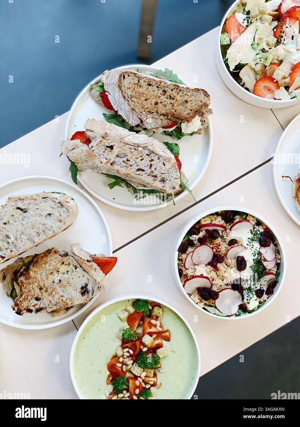 Pranzo salutare al caffè con panini, insalate e zuppe, vista dall'alto su un tavolo leggero Foto Stock