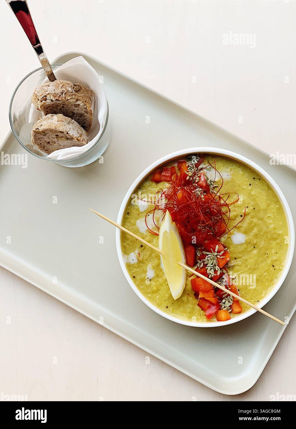 Vista dall'alto di una zuppa di verdure gourmet splendidamente arredata, guarnita con limone, peperoni rossi, semi di finocchio e fili di peperoncino Foto Stock