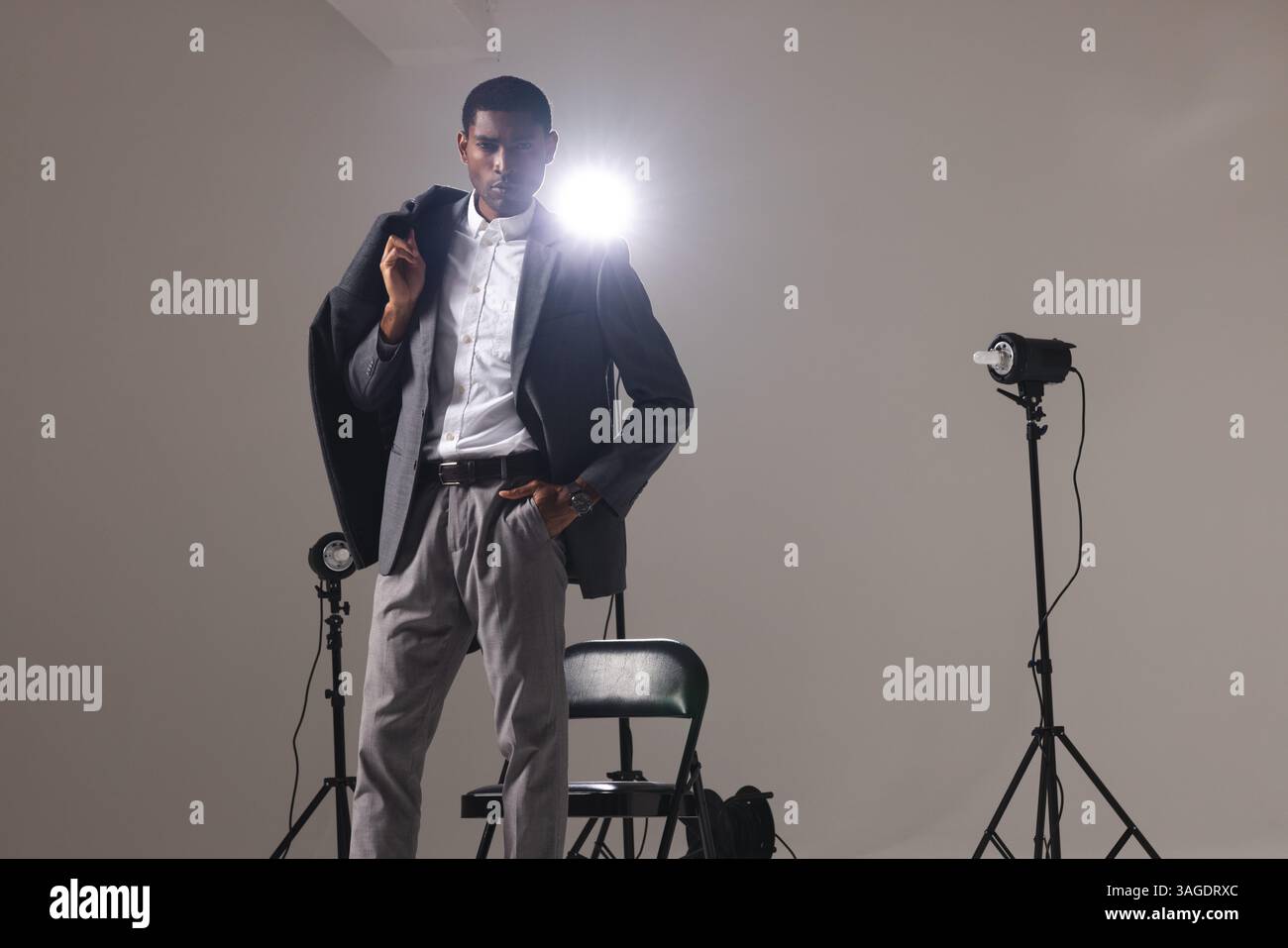 Uomo sicuro di sé in un abito elegante che posa sotto le luci dello studio, mostrando stile. stile, modellazione, abbigliamento da uomo, eleganza, ritratto, formale Foto Stock