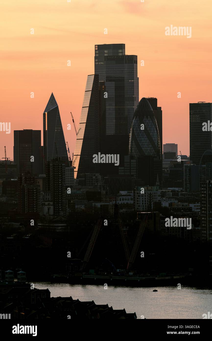 Lo skyline della città di Londra si staglia al tramonto, con il Gherkin, il bisturi e il 22 Bishopsgate contro un cielo arancione brillante Foto Stock