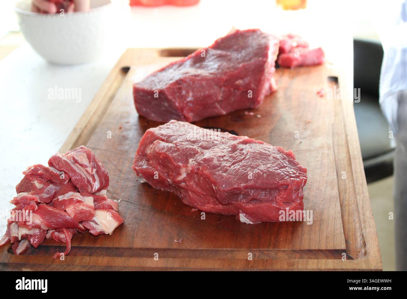 Lo chef taglia la carne cruda in un tagliere Foto Stock