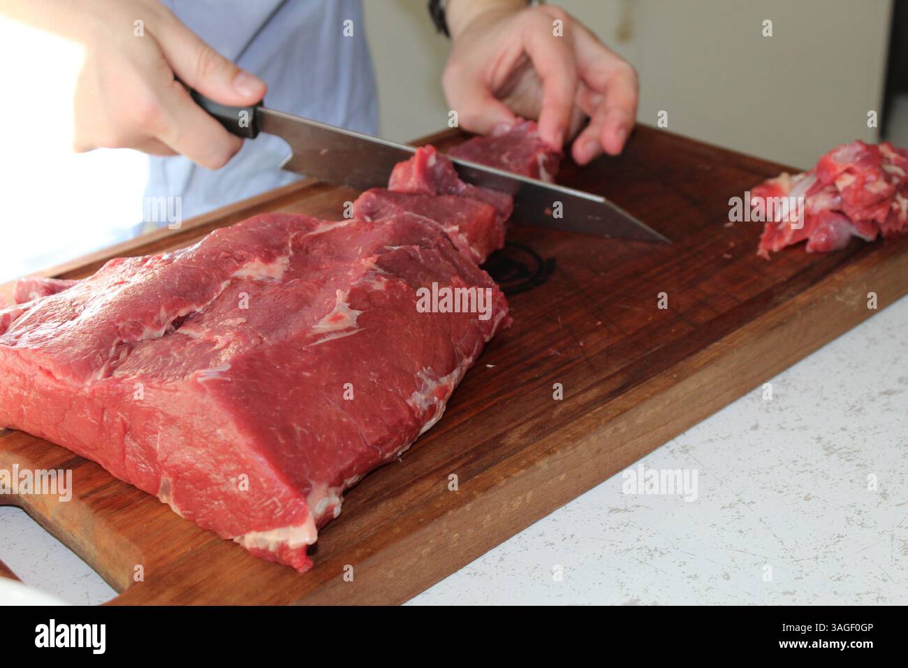 Lo chef taglia la carne cruda in un tagliere Foto Stock