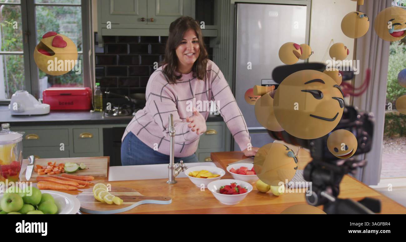 Immagine di icone emoji sopra una vlogger culinario femminile che registra vlog a casa Foto Stock