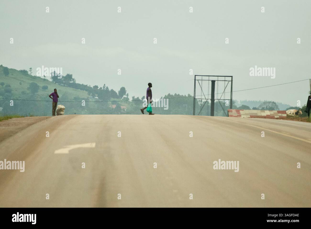 Un uomo attraversa una strada con una borsa in mano in Uganda, Africa Foto Stock