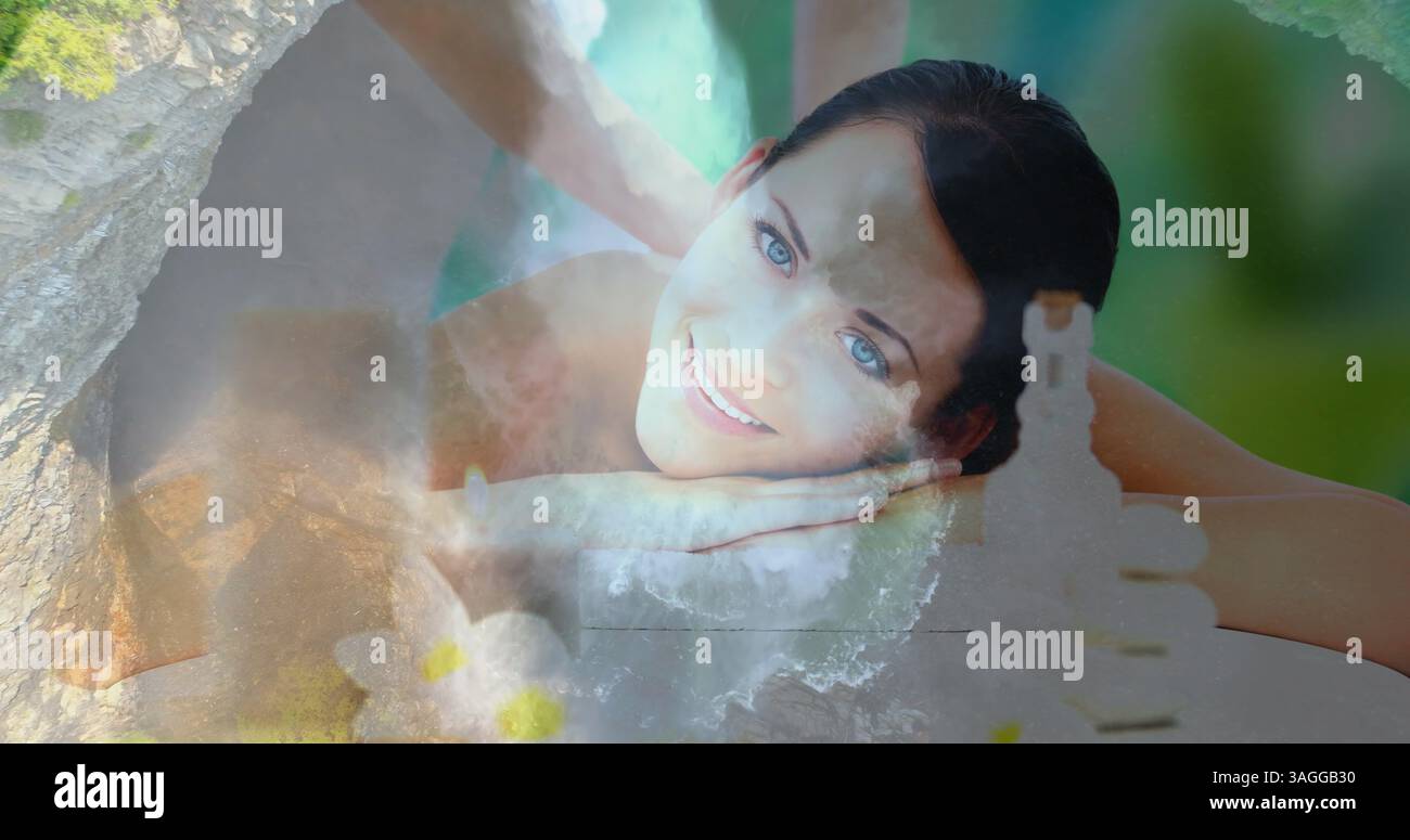 Donna sorridente che riceve un massaggio sulla tranquilla scena della natura con cascate Foto Stock