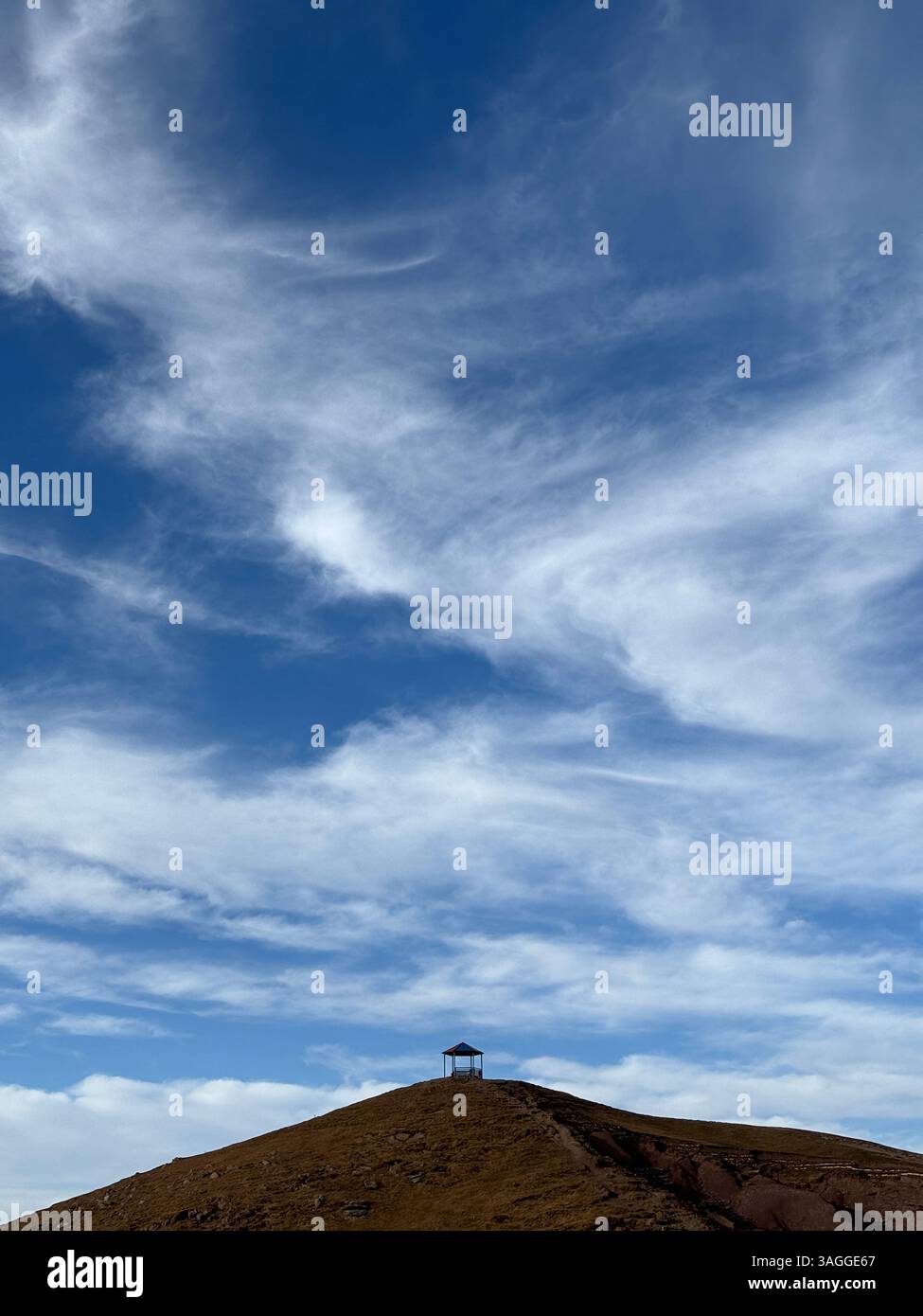 Capanna in cima alla collina con cielo ampio e nuvole blu - Immagine stock catturata con smartphone
