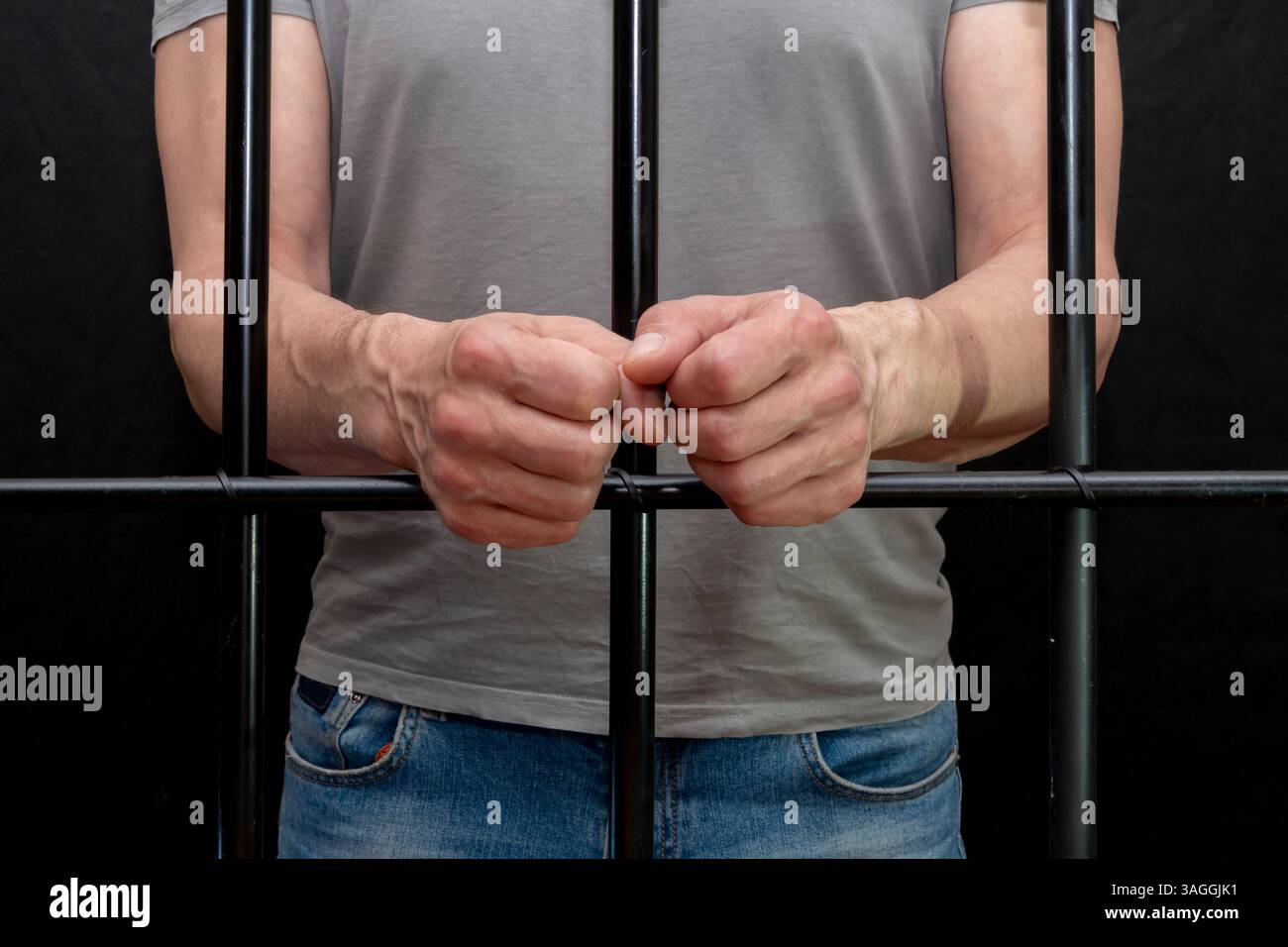 Primo piano delle mani di un prigioniero che si aggrappano alle sbarre Foto Stock