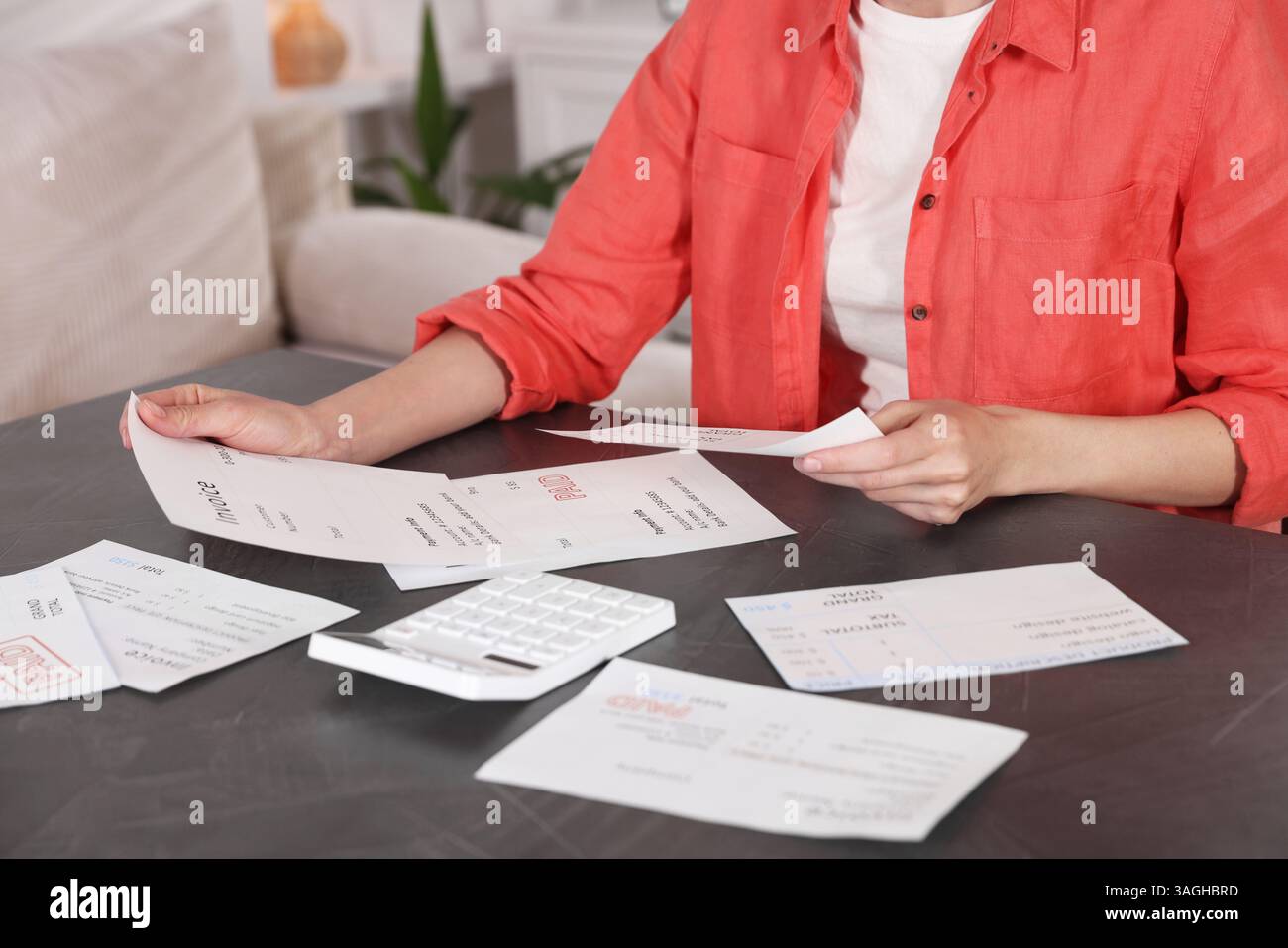 Pagare le bollette. Donna con calcolatrice e fatture al tavolo al chiuso Foto Stock