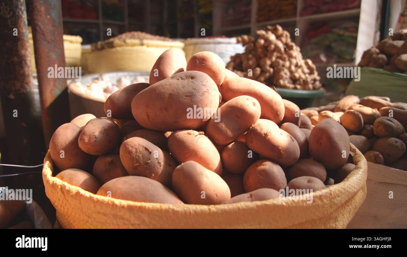 Una bancarella di verdure con patate fresche e zenzero, che mette in evidenza prodotti naturali e freschi in un vivace ambiente di mercato. Foto Stock