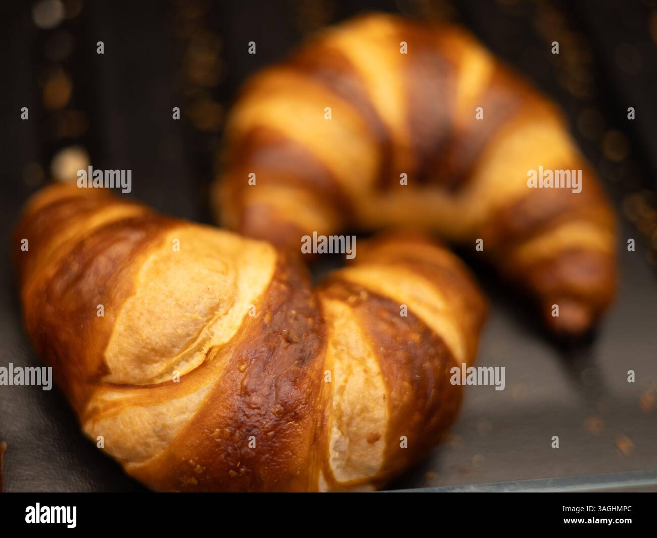 Due eleganti croissant a righe che invitano a viziarvi con la loro ricchezza burrosa e la loro consistenza friabile per una deliziosa colazione. Foto Stock