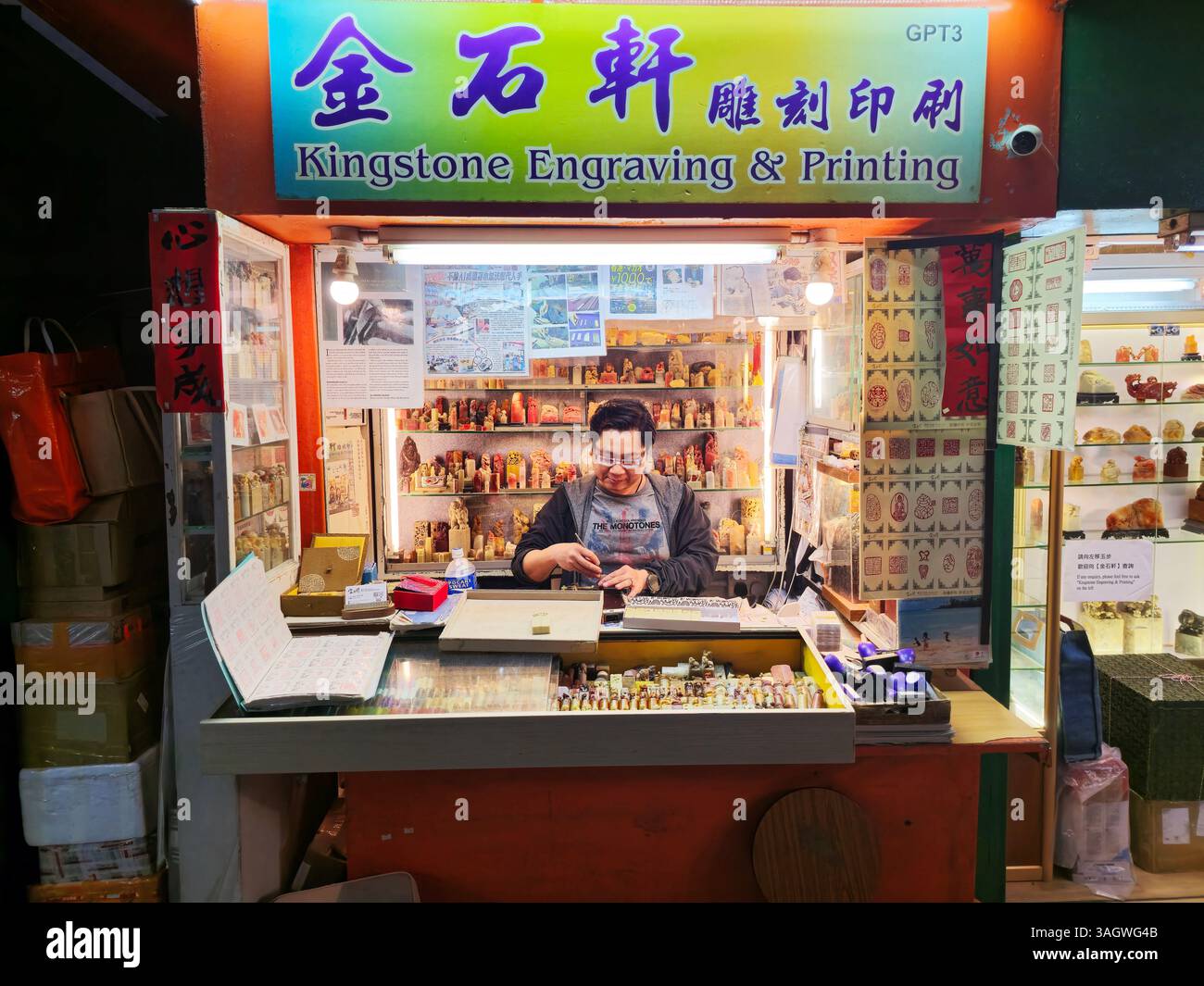 Un artigiano che lavora su sigilli cinesi tradizionali in pietra esposto in un negozio di artigianato a Man Wa Lane nel quartiere centrale di Hong Kong. Foto Stock