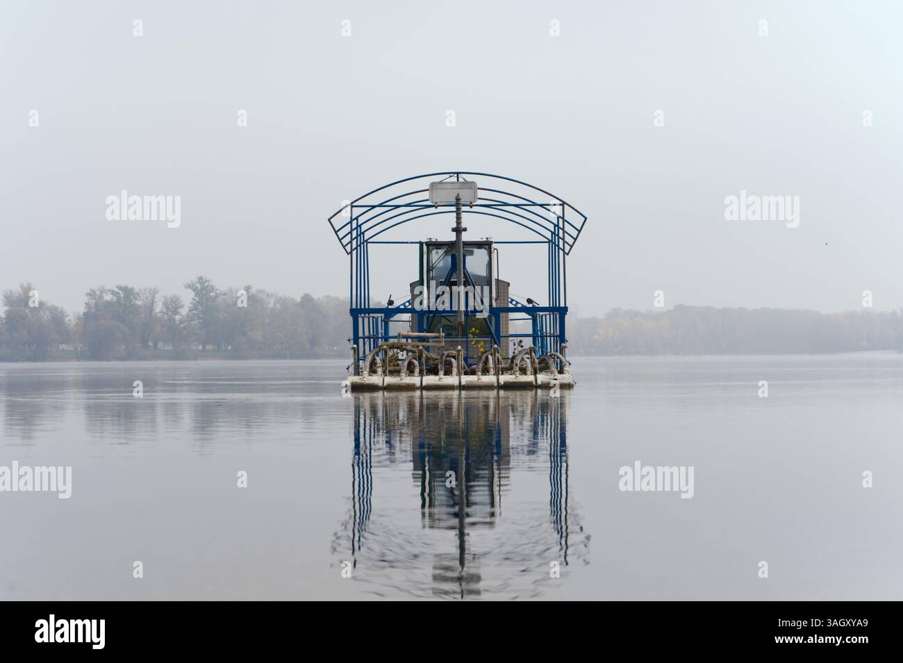 Una piattaforma galleggiante blu con struttura in metallo si snoda tranquillamente su un lago calmo. Foto Stock Una piattaforma galleggiante blu con struttura in metallo si snoda tranquillamente su un lago calmo. Foto Stock