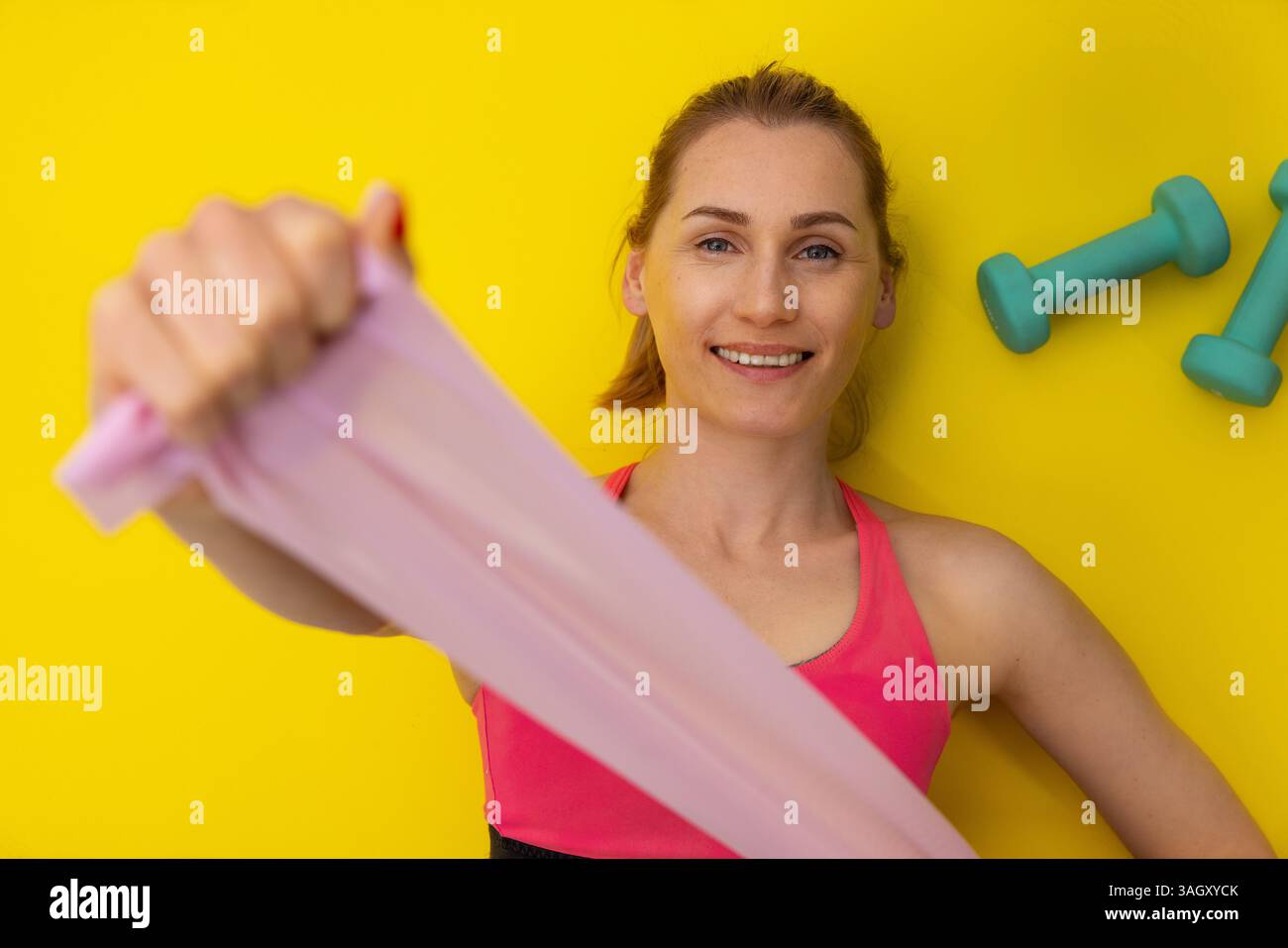 esercizi con bande di resistenza. la donna si sta sdraiando su un tappetino giallo per il fitness e si allena. vista dall'alto Foto Stock